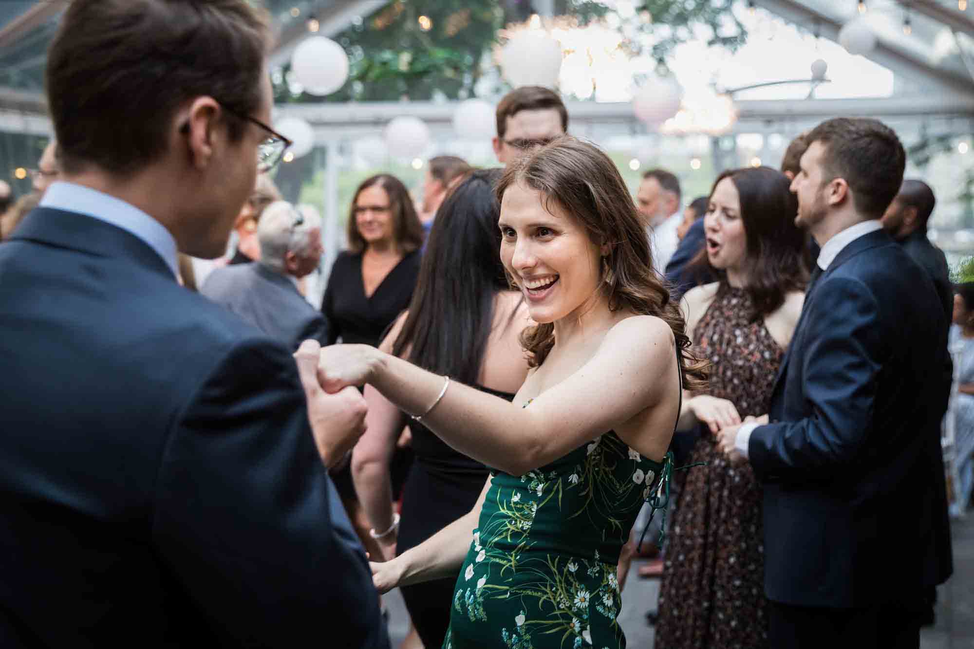 Woman in green dress dancing with man in front of guests at a Sanctuary Roosevelt Island wedding