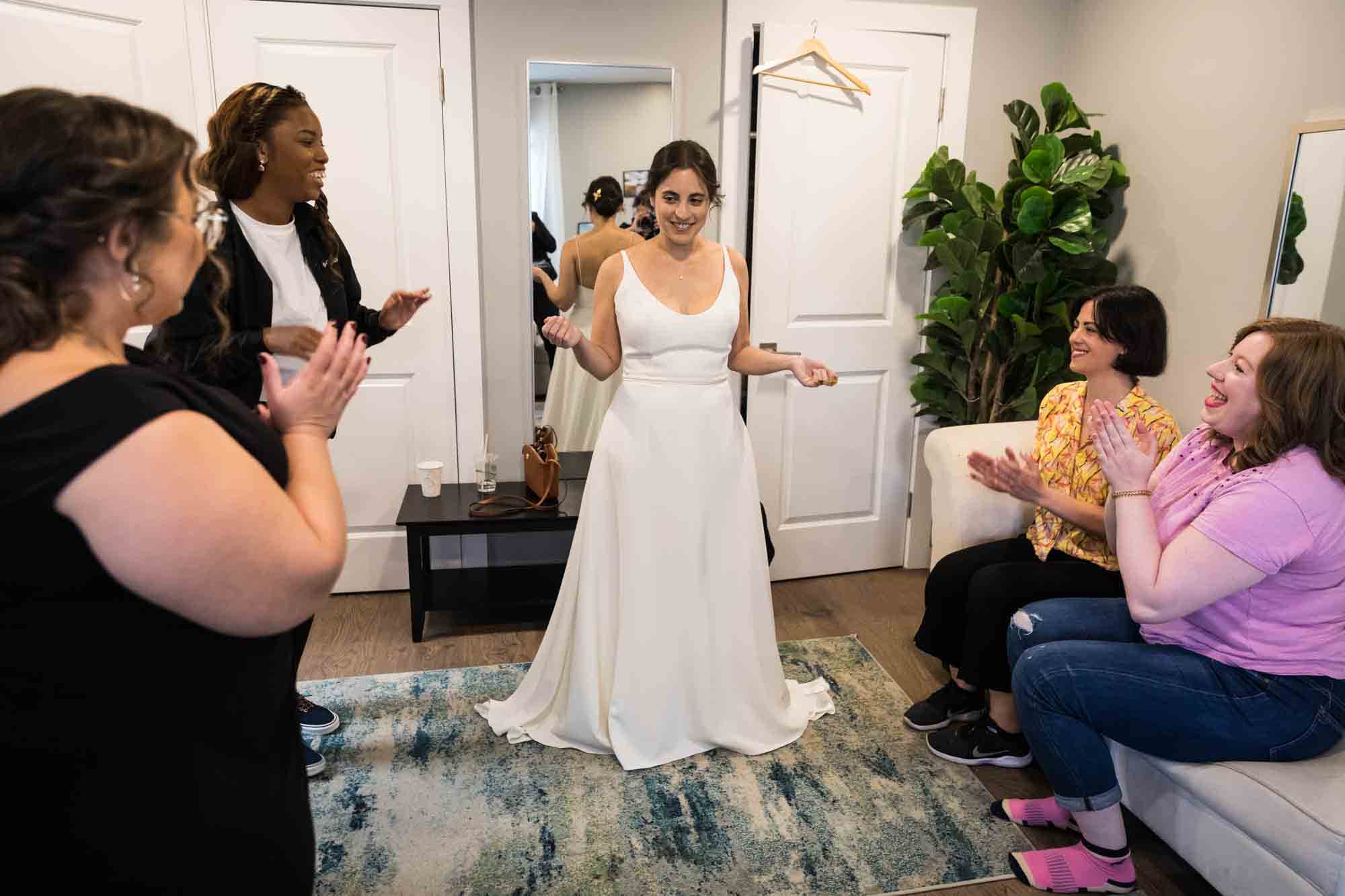 Bride wearing white wedding dress in front of four female friends in room at a Sanctuary Roosevelt Island wedding