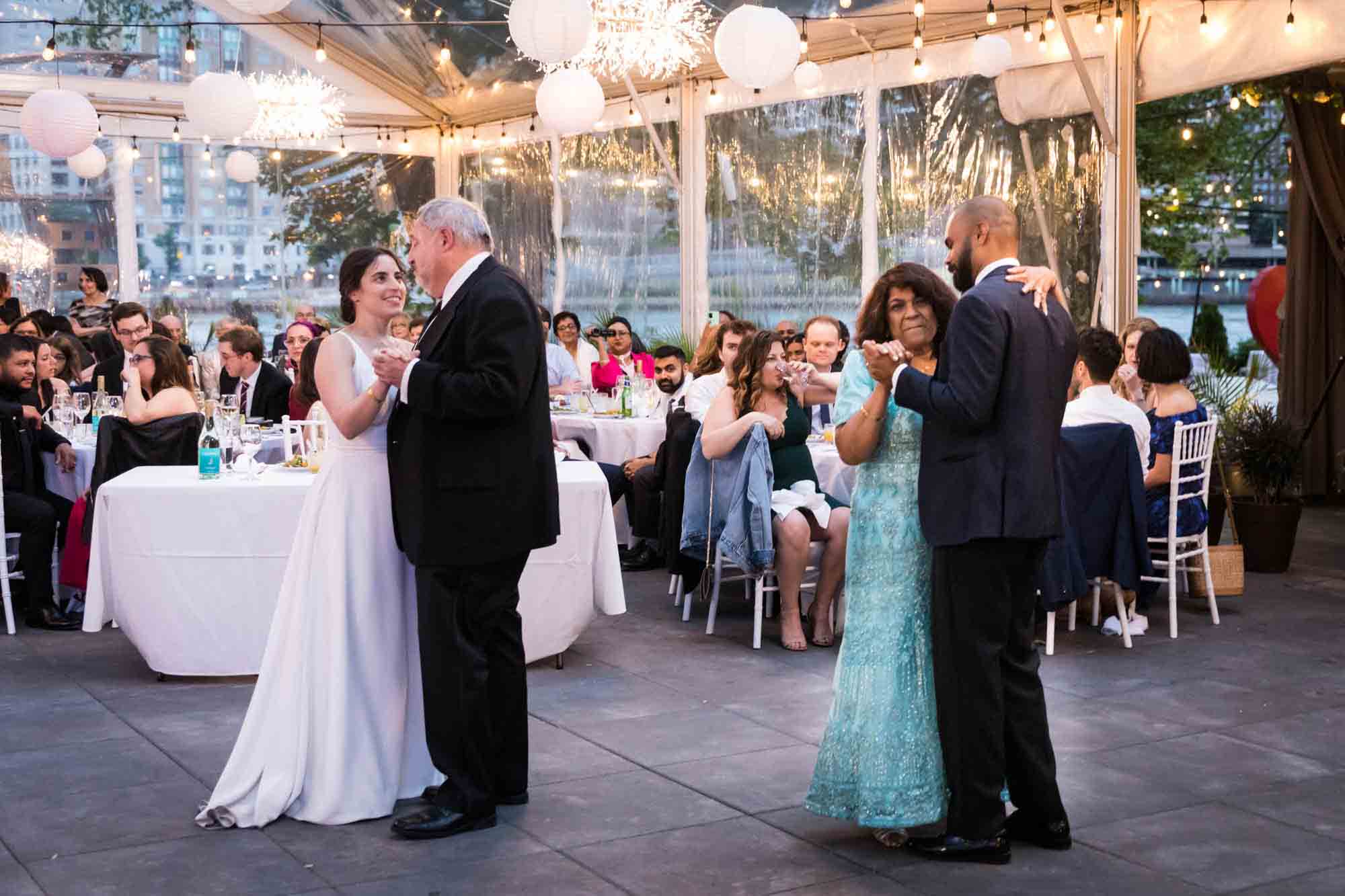Bride and groom dancing with parents in front of guests under clear tent at a Sanctuary Roosevelt Island wedding