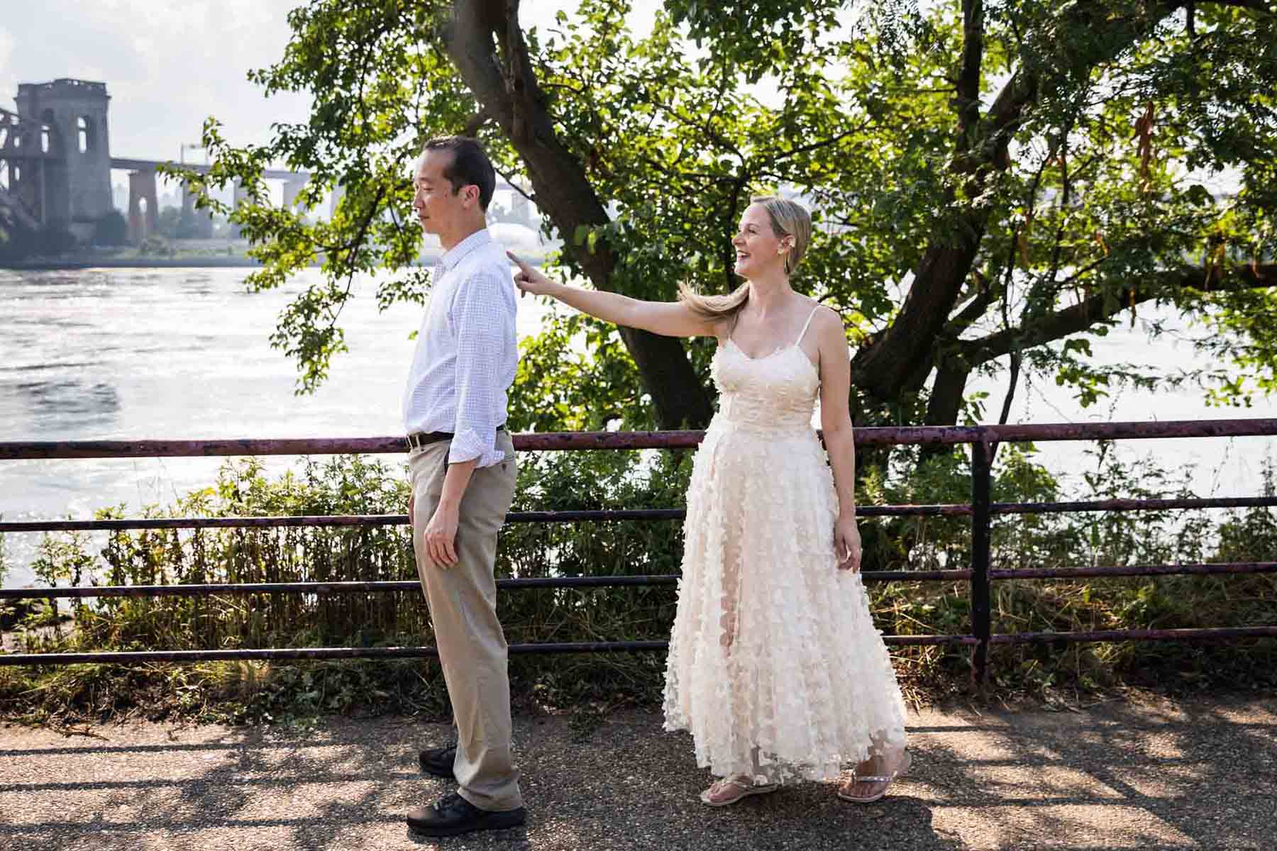 Astoria Park engagement photos of a couple reenacting their 'first look' along waterfront