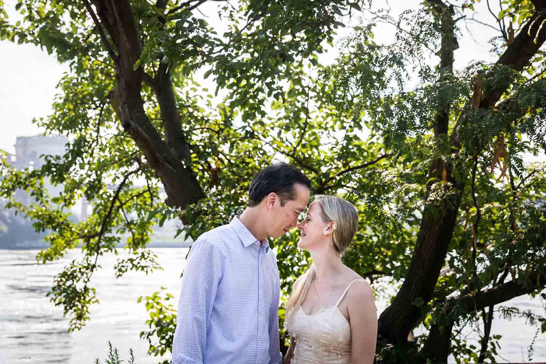 Astoria Park engagement photos of a couple touching foreheads along waterfront