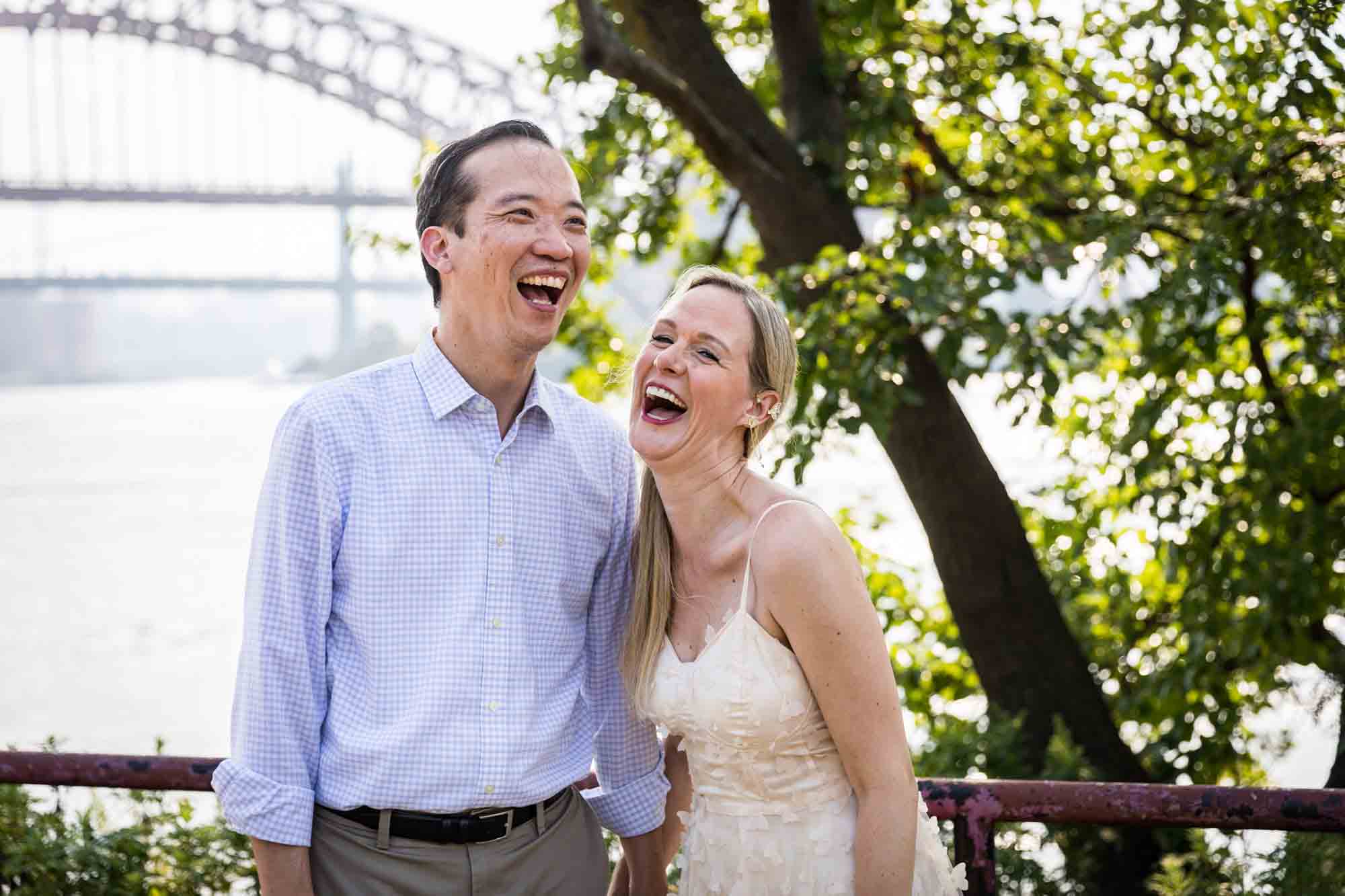 Astoria Park engagement photos of a couple laughing along waterfront