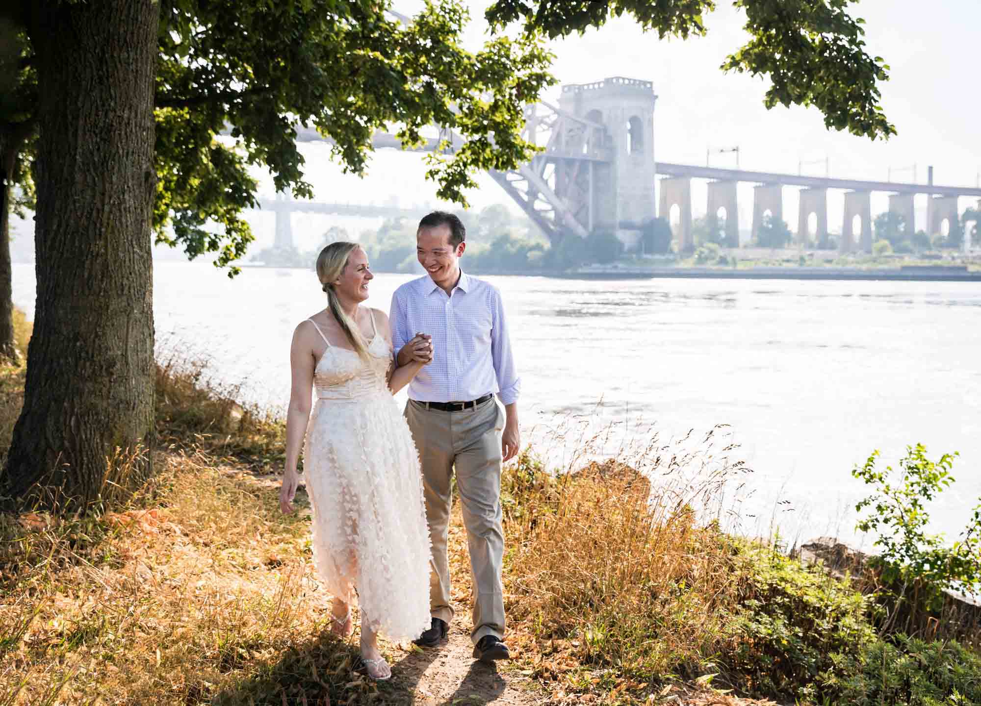 Astoria Park engagement photos of a couple walking along waterfront
