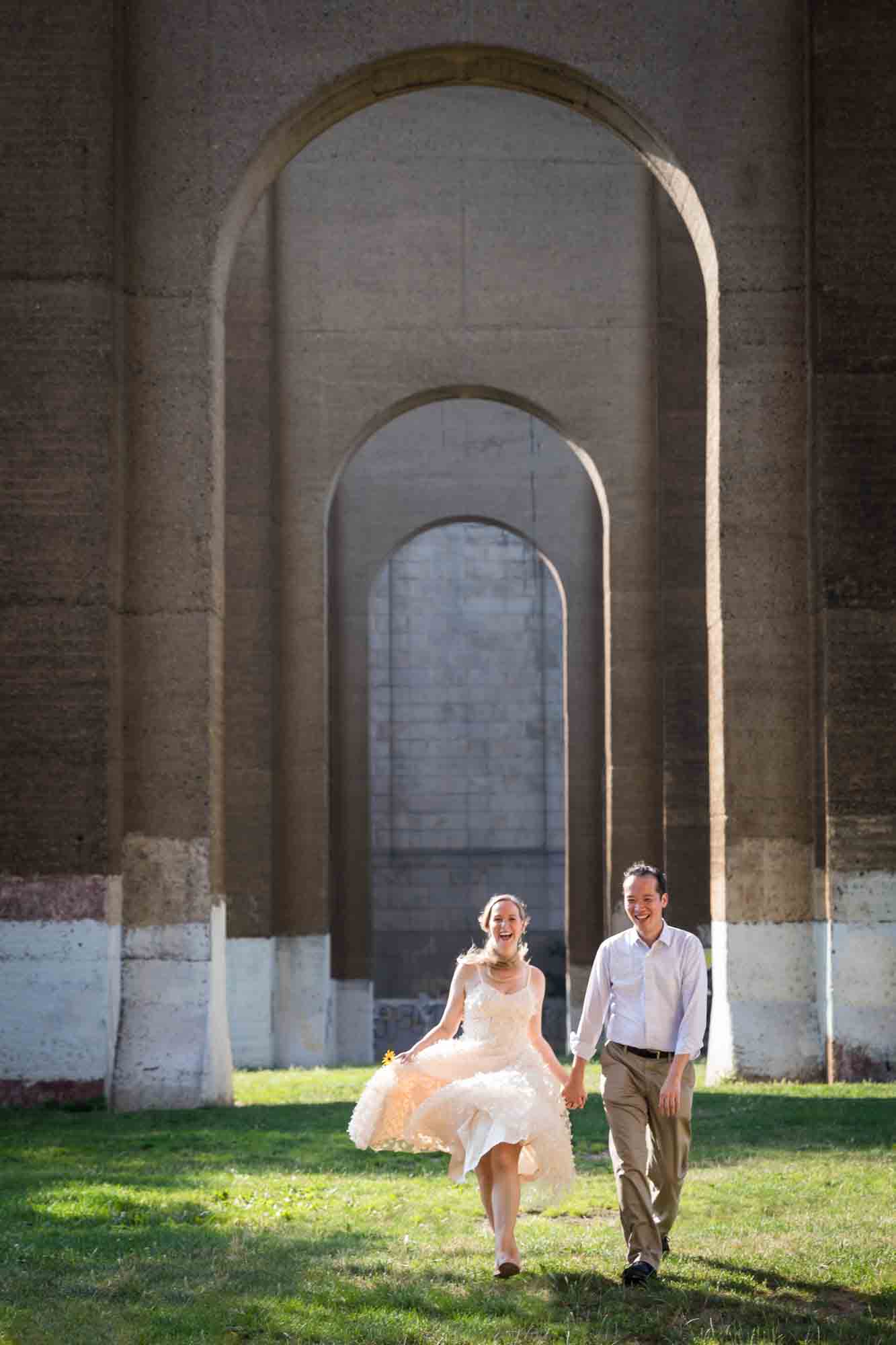 Astoria Park engagement photos of a couple skipping under the Hell Gate Bridge