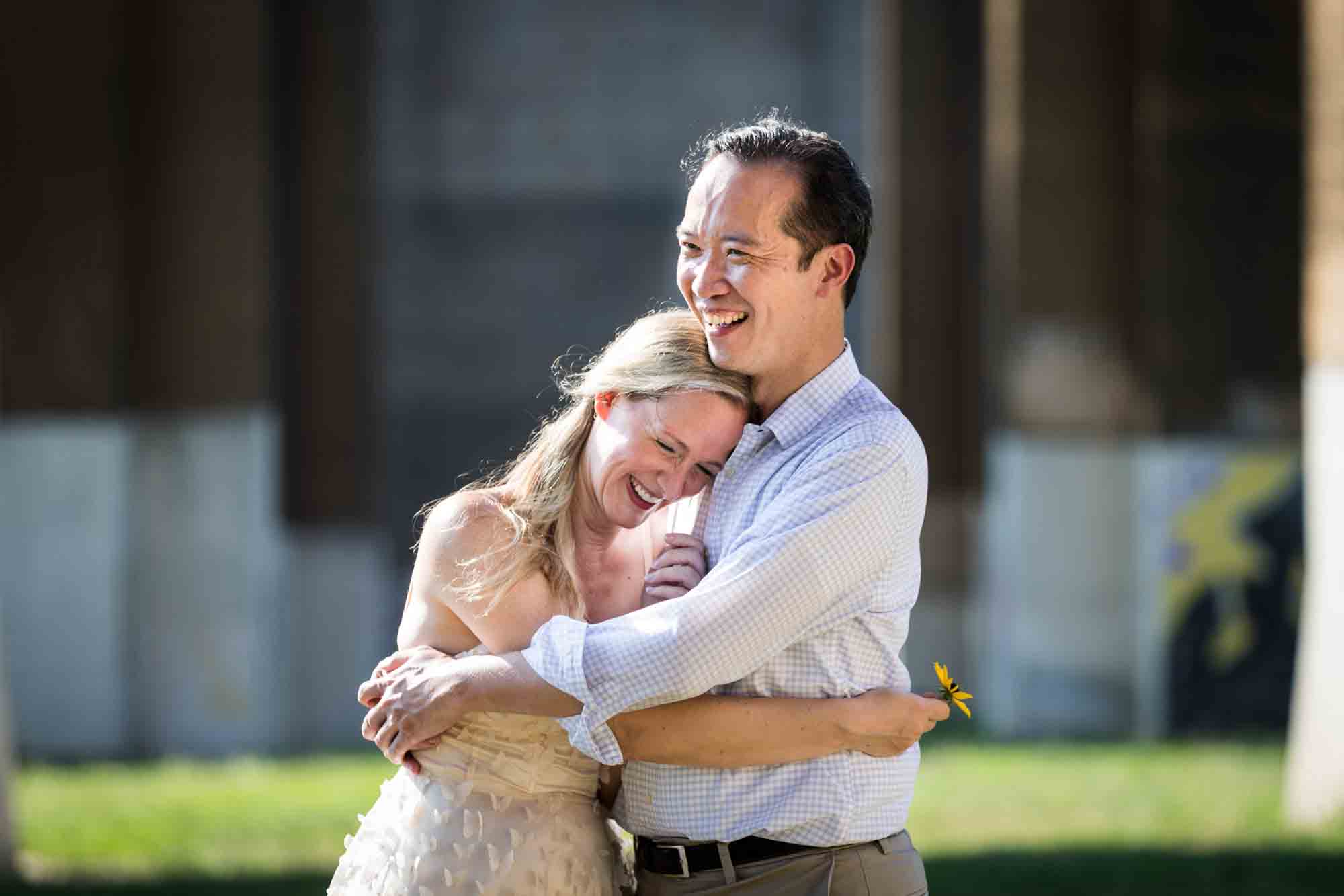 Astoria Park engagement photos of a couple hugging under the Hell Gate Bridge