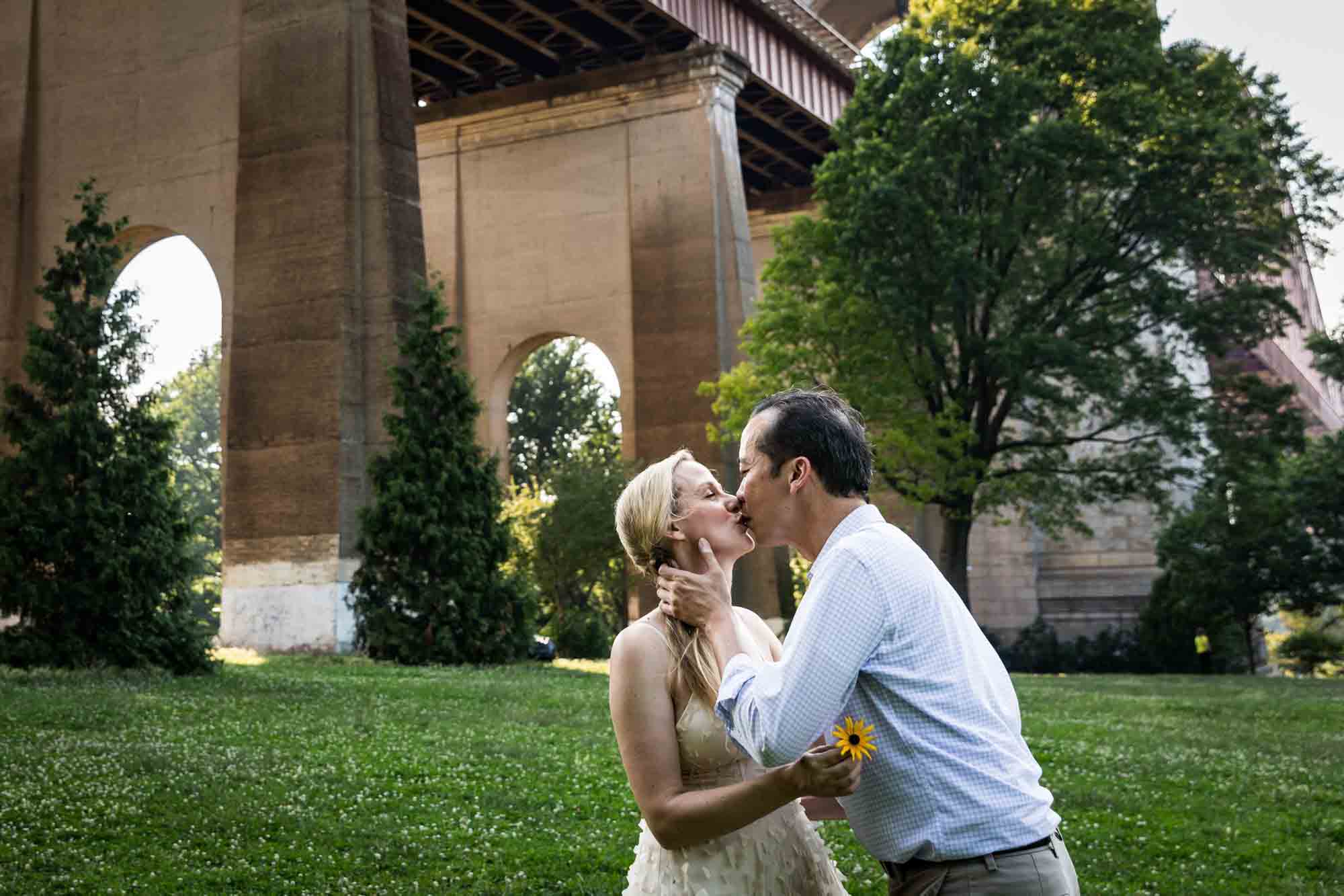 Astoria Park engagement photos of a couple kissing in front of Hell Gate Bridge