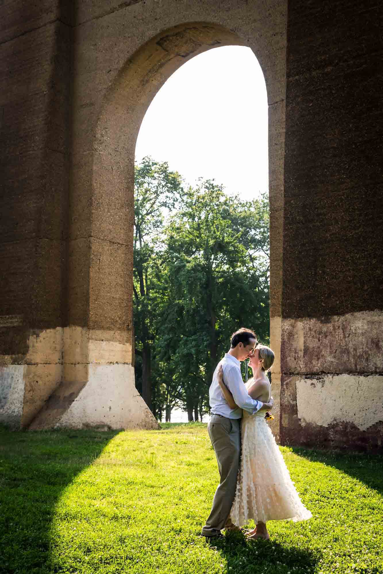 Astoria Park engagement photos of a couple kissing under Hell Gate Bridge