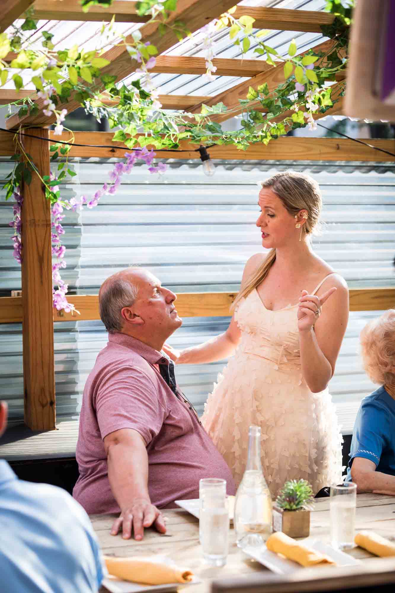 Bride talking with father at outdoor restaurant during rehearsal dinner
