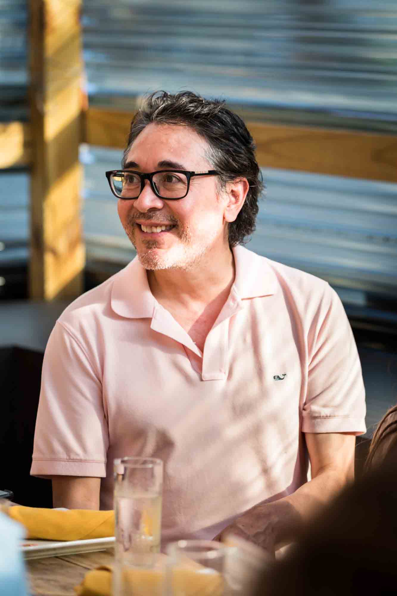 Man wearing glasses and pink shirt during rehearsal dinner