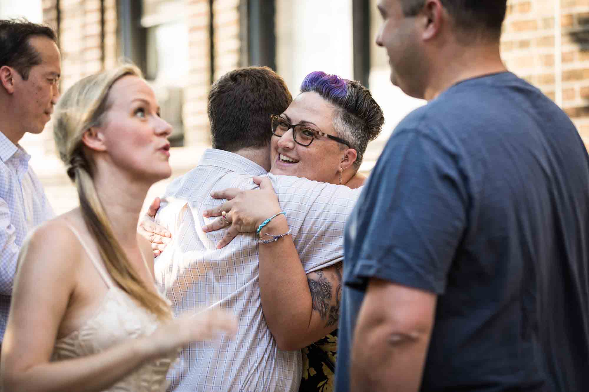 Guests hugging on the sidewalk during rehearsal dinner at an outdoor restaurant
