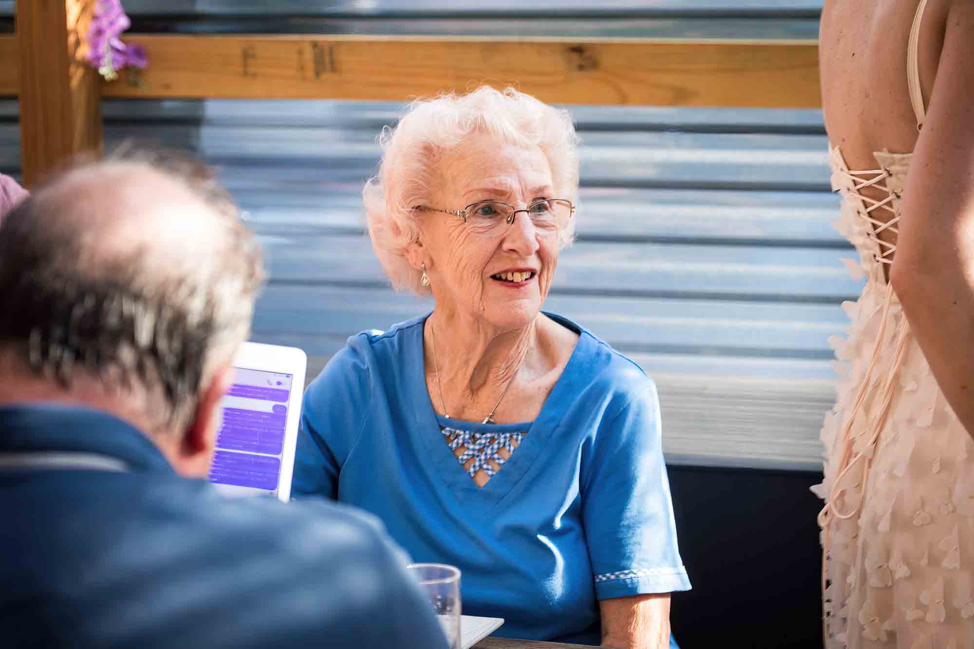 Older woman wearing blue blouse during rehearsal dinner at an outdoor restaurant