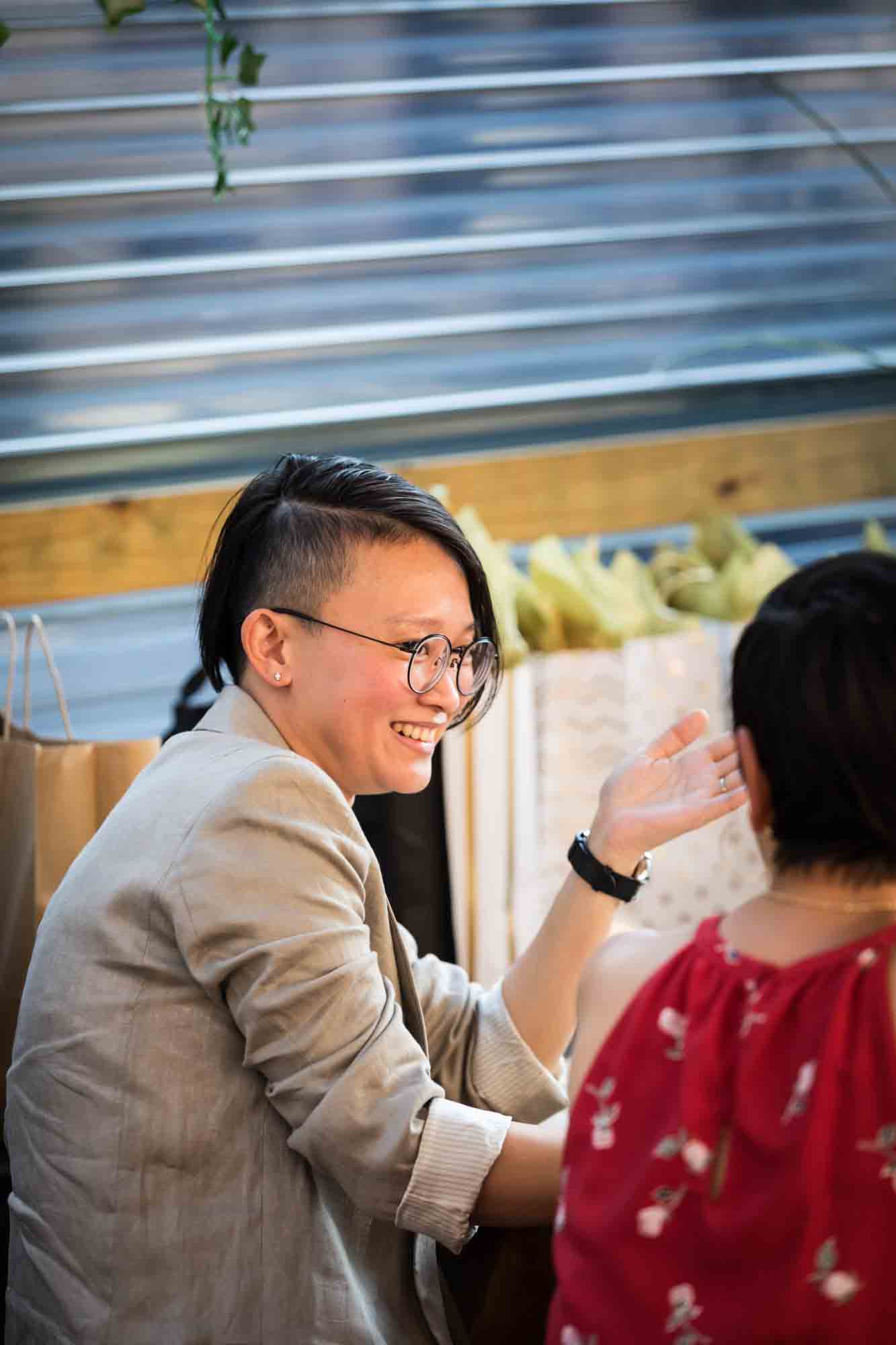 Asian woman with shaved hair during rehearsal dinner at an outdoor restaurant