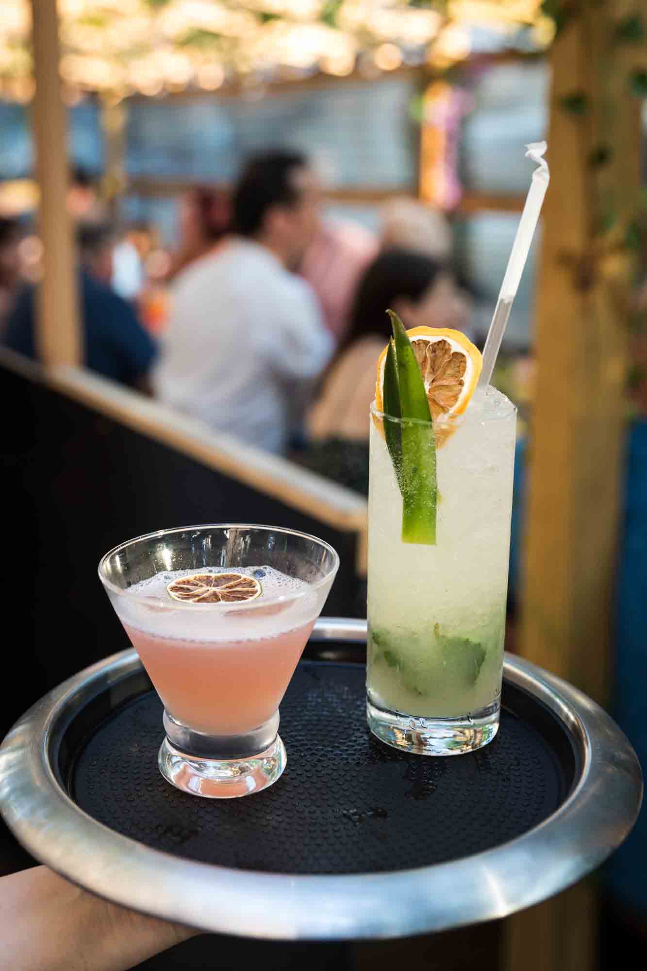 Tray with two colorful cocktails during rehearsal dinner at an outdoor restaurant