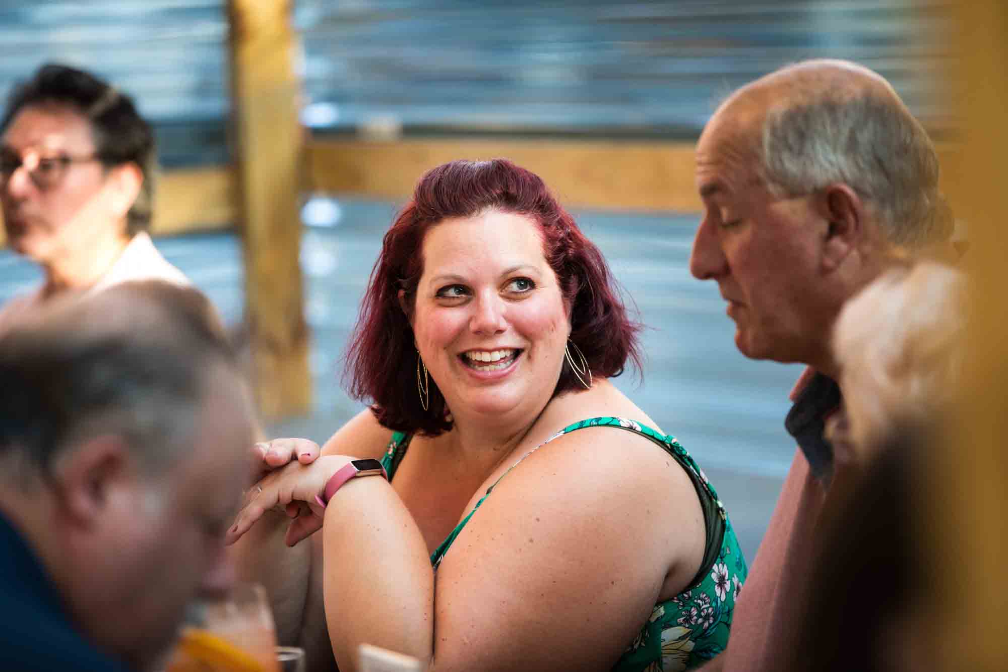 Woman with red hair chatting during rehearsal dinner at an outdoor restaurant