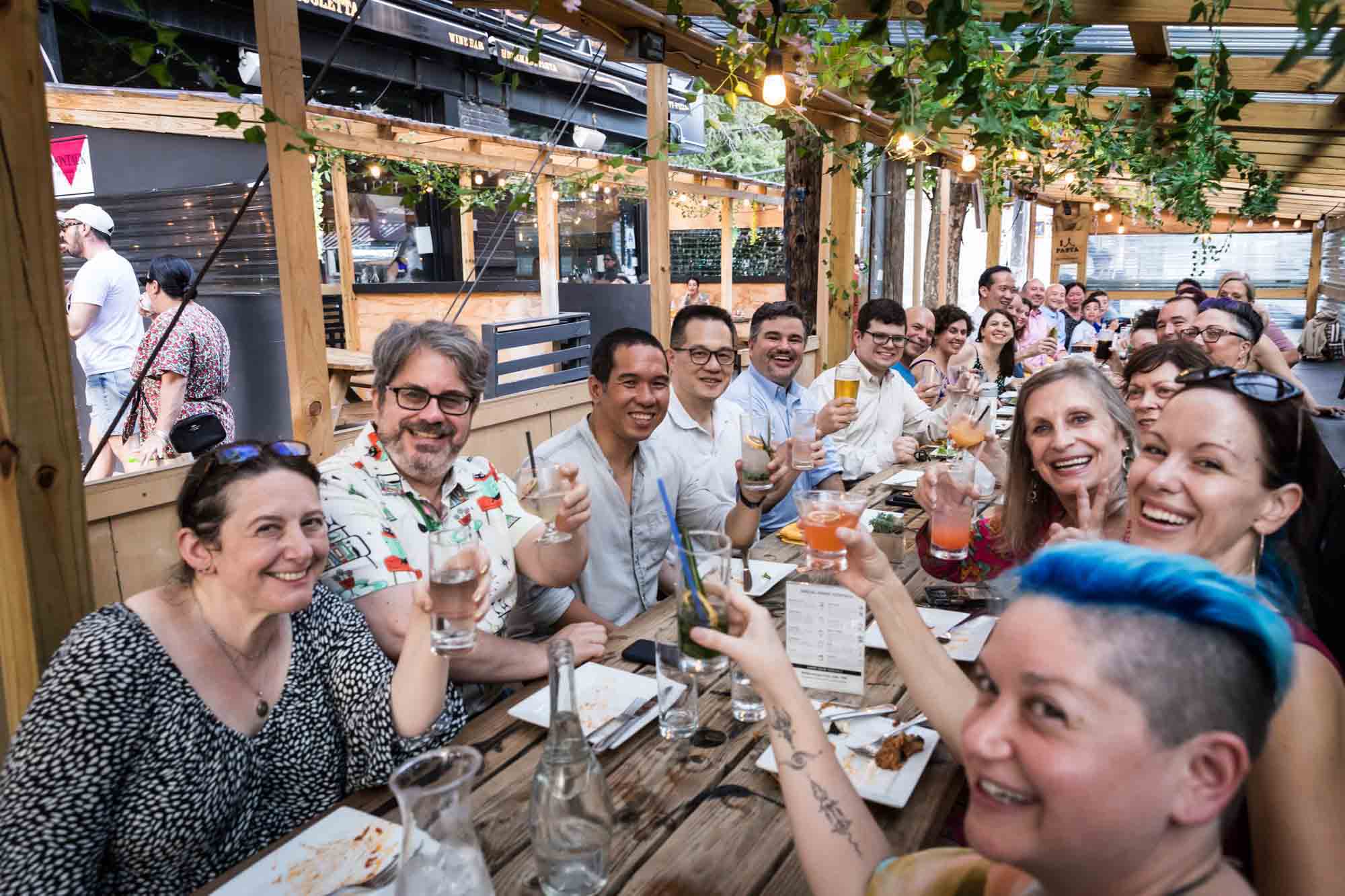 Group photo of seated guests during rehearsal dinner at an outdoor restaurant