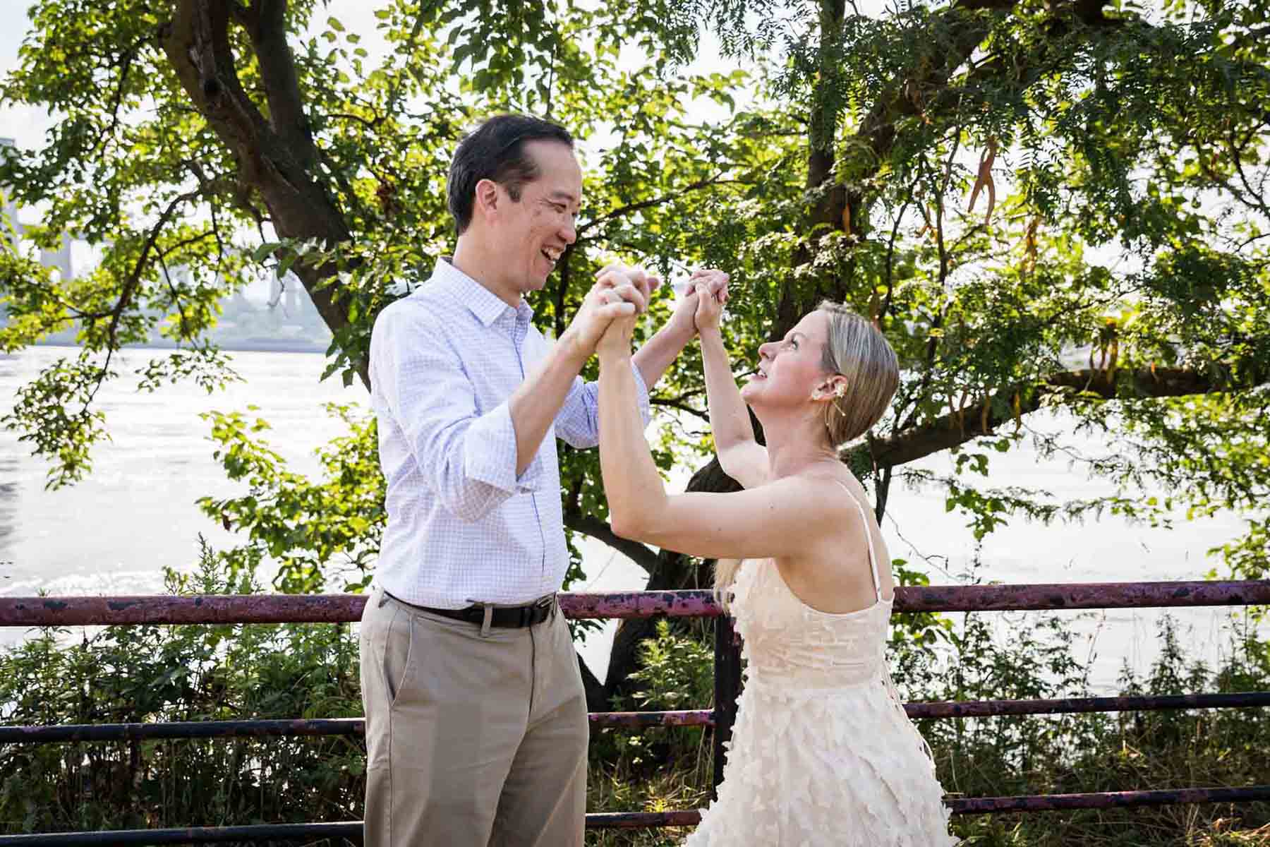 Astoria Park engagement photos of a couple play fighting along waterfront