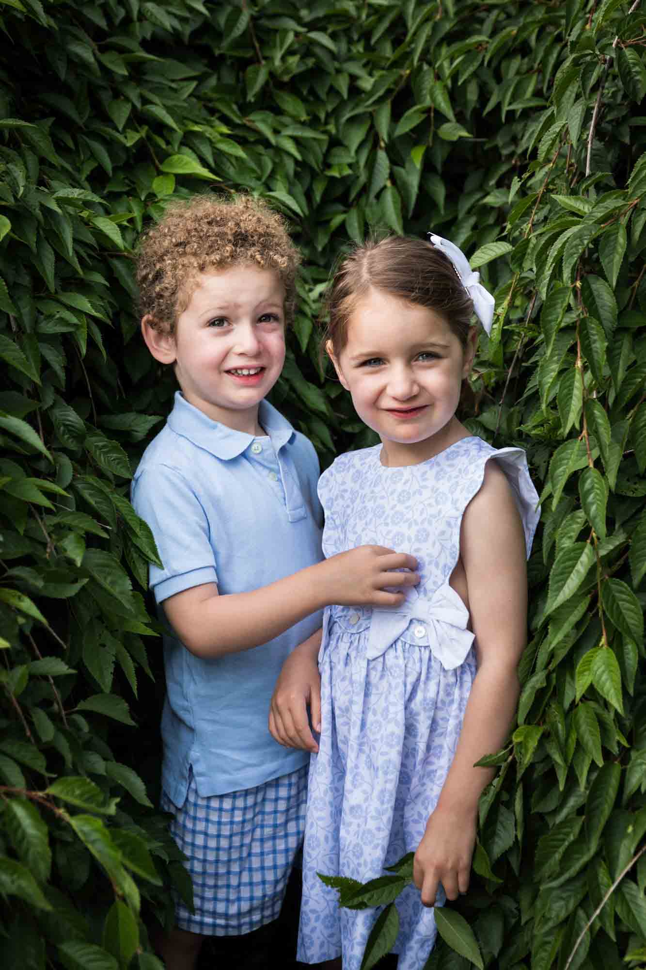 Little girl and boy standing in front of bushes during a Narrows Botanical Gardens family portrait session