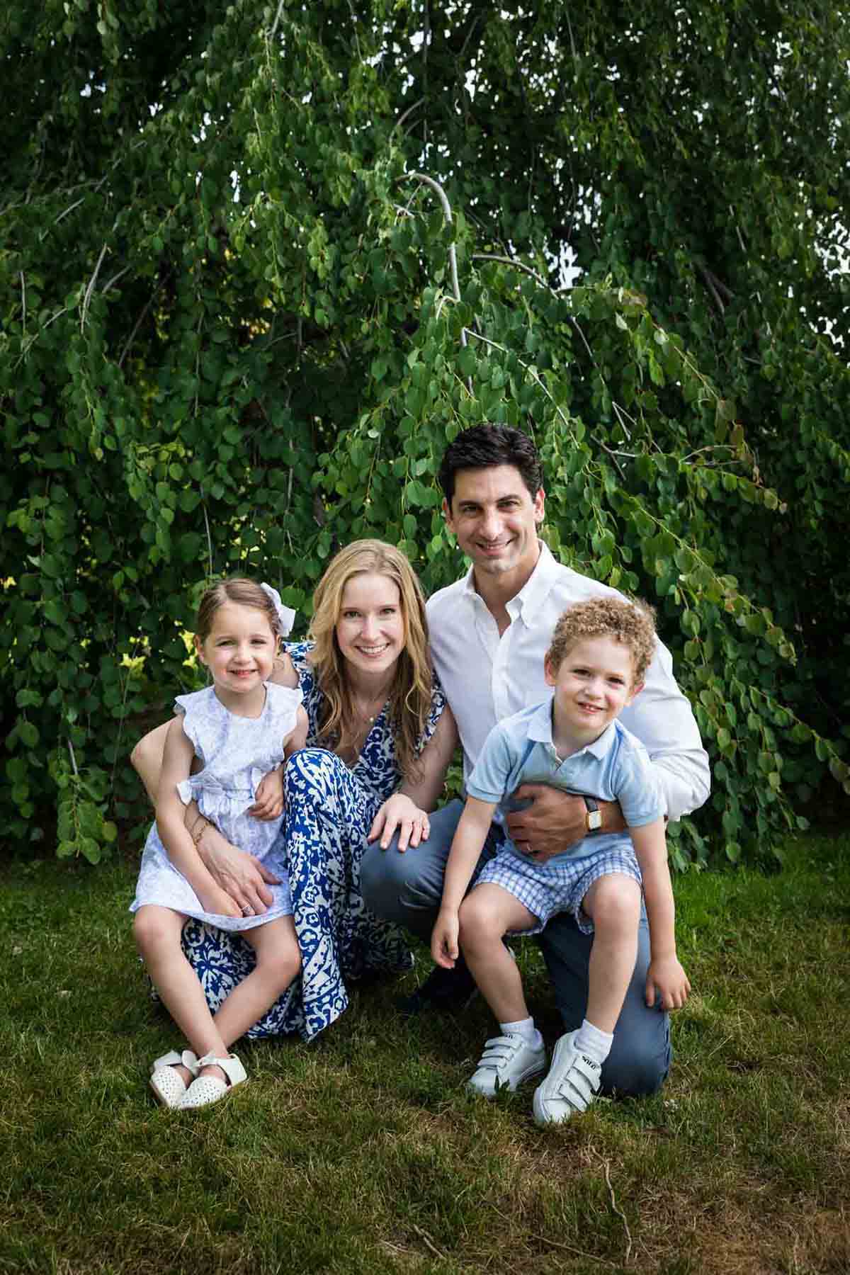 Parents holding little boy and little girl in front of trees during a Narrows Botanical Gardens family portrait session