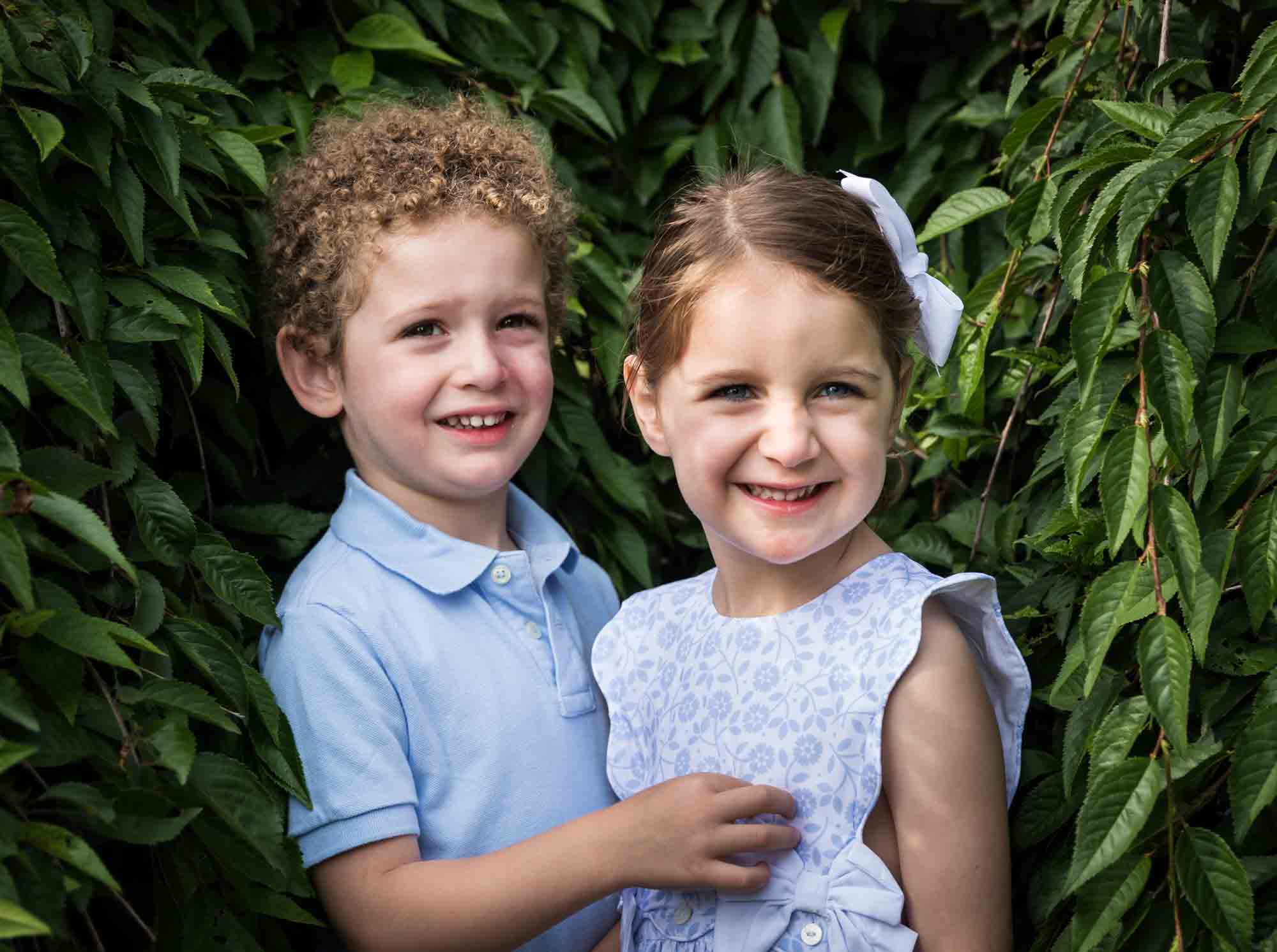 Little girl and boy standing in front of bushes during a Narrows Botanical Gardens family portrait session