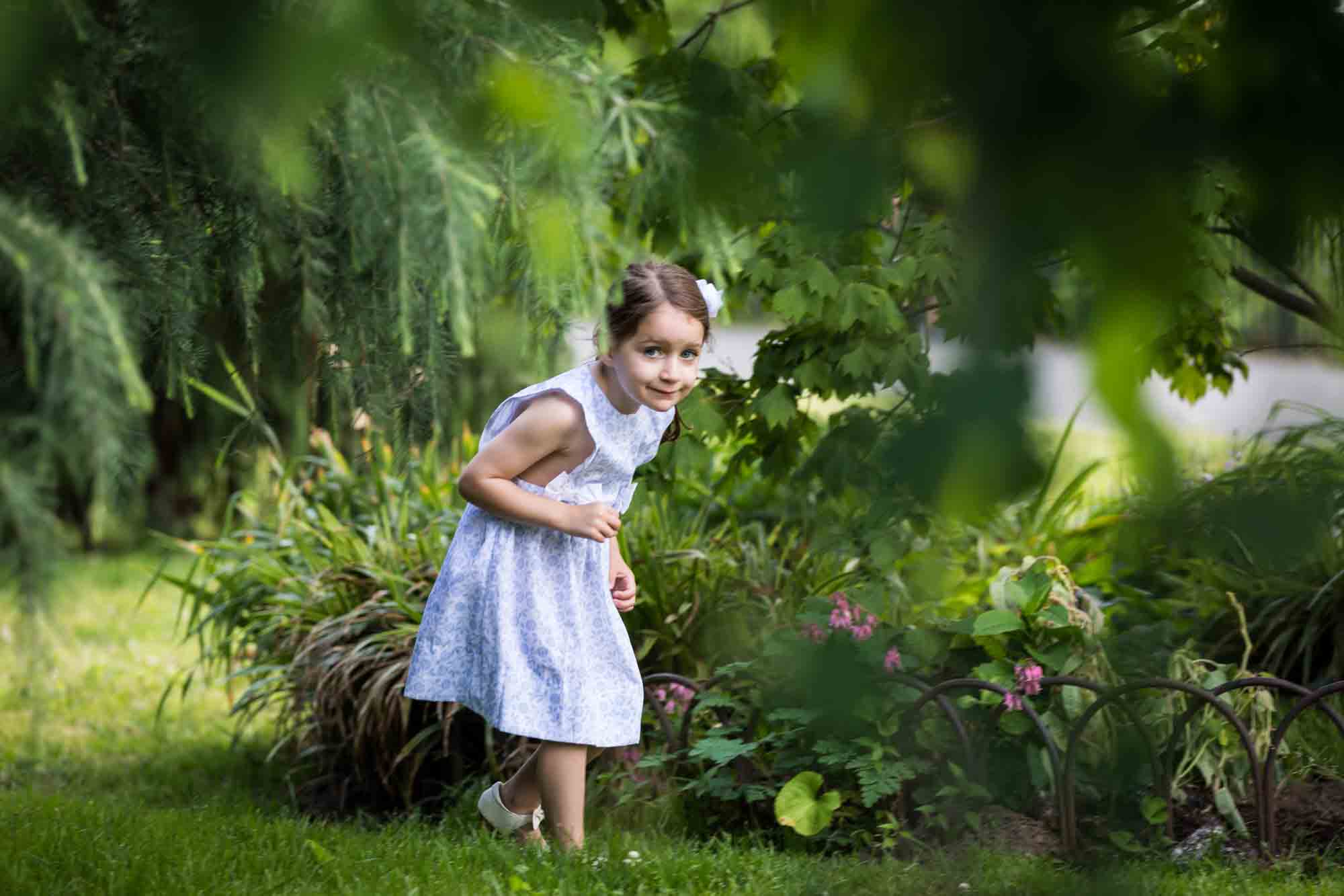 Little girl in blue dress walking in front of plant bed during a Narrows Botanical Gardens family portrait session
