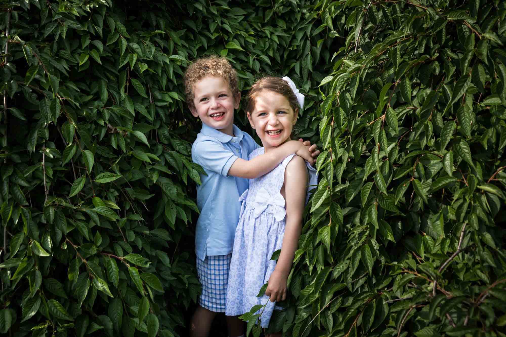 Little boy and girl hugging in front of bushes during a Narrows Botanical Gardens family portrait session