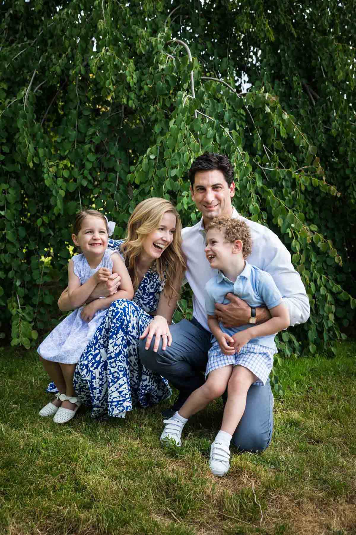 Parents holding little boy and little girl in front of trees during a Narrows Botanical Gardens family portrait session