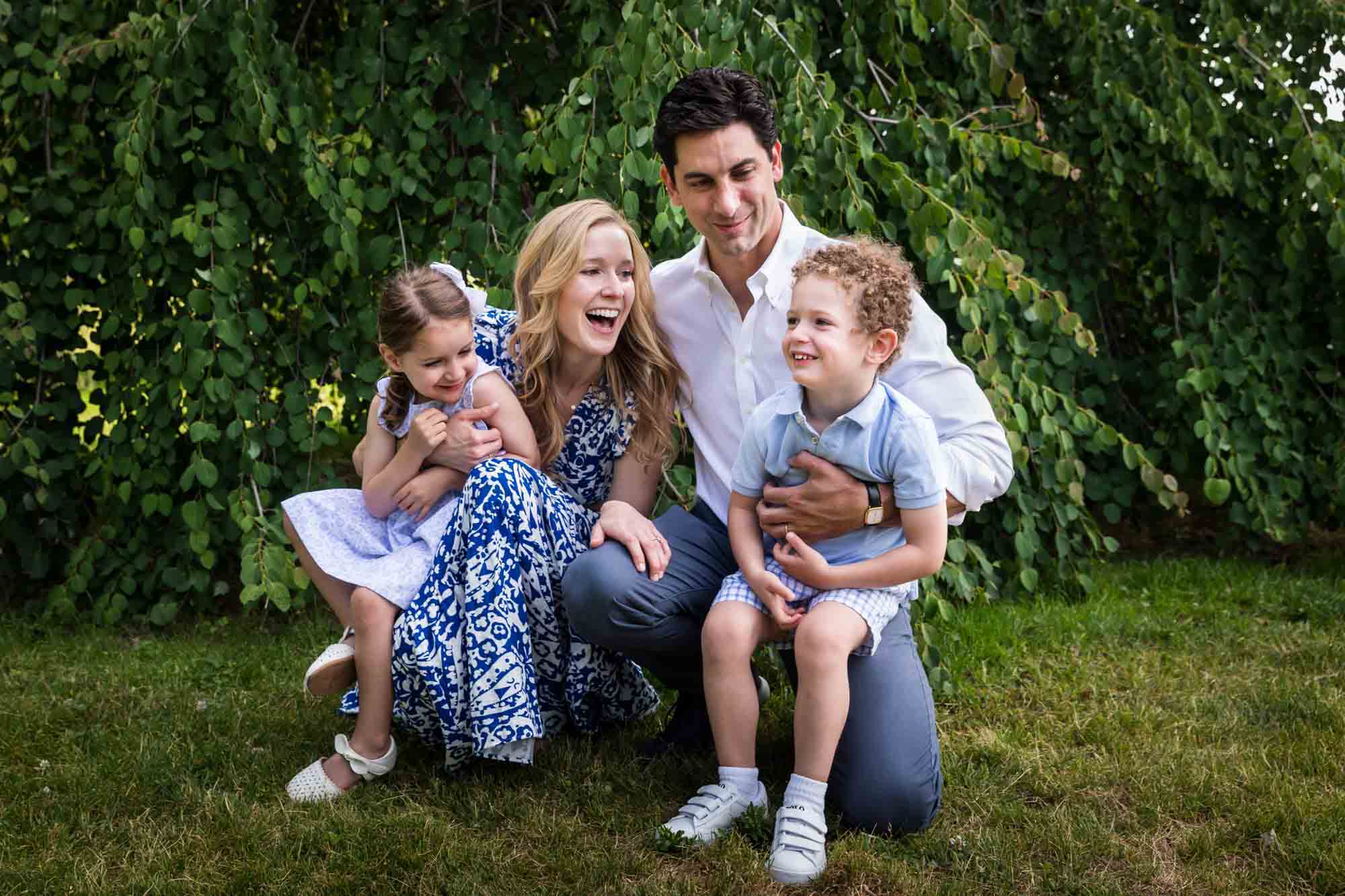 Parents holding little boy and little girl in front of trees during a Narrows Botanical Gardens family portrait session