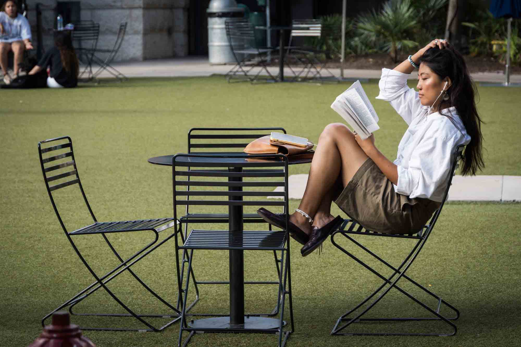 Woman sitting at table reading a book on patio of The Pearl in San Antonio