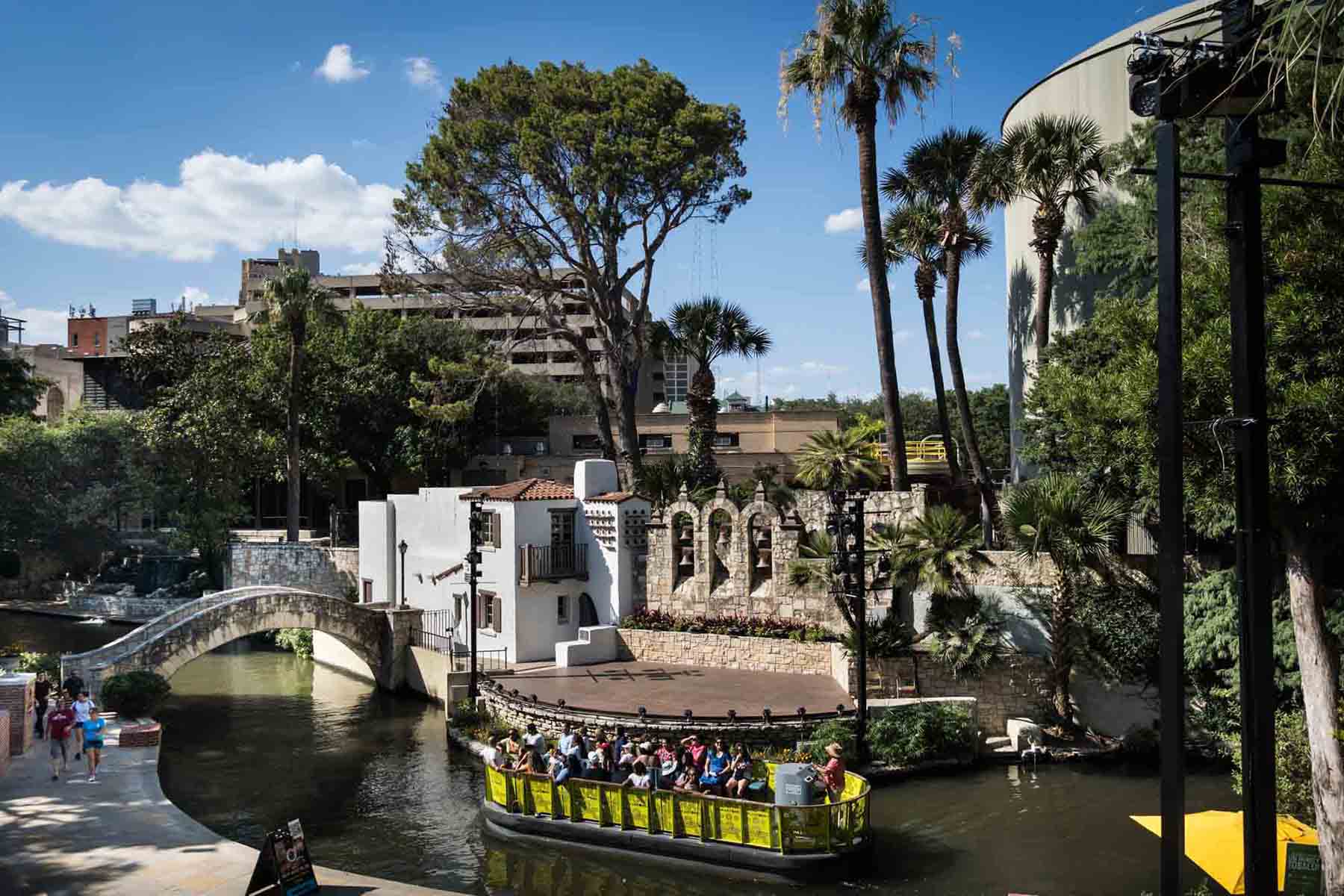 Yellow boat on the Riverwalk sailing past the Ameson River Theatre in San Antonio