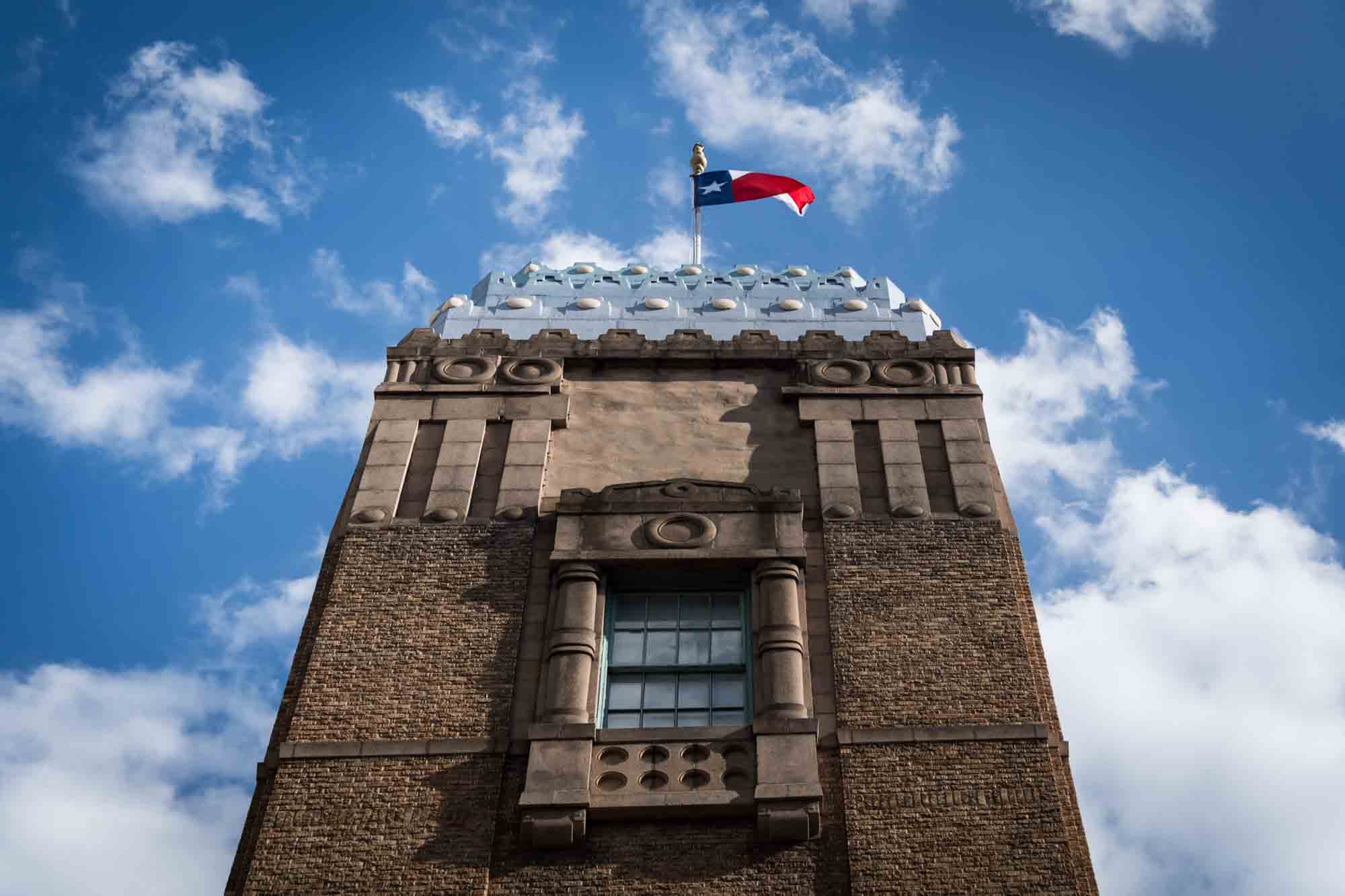 Building with Texas state flag on top in front of blue sky in San Antonio