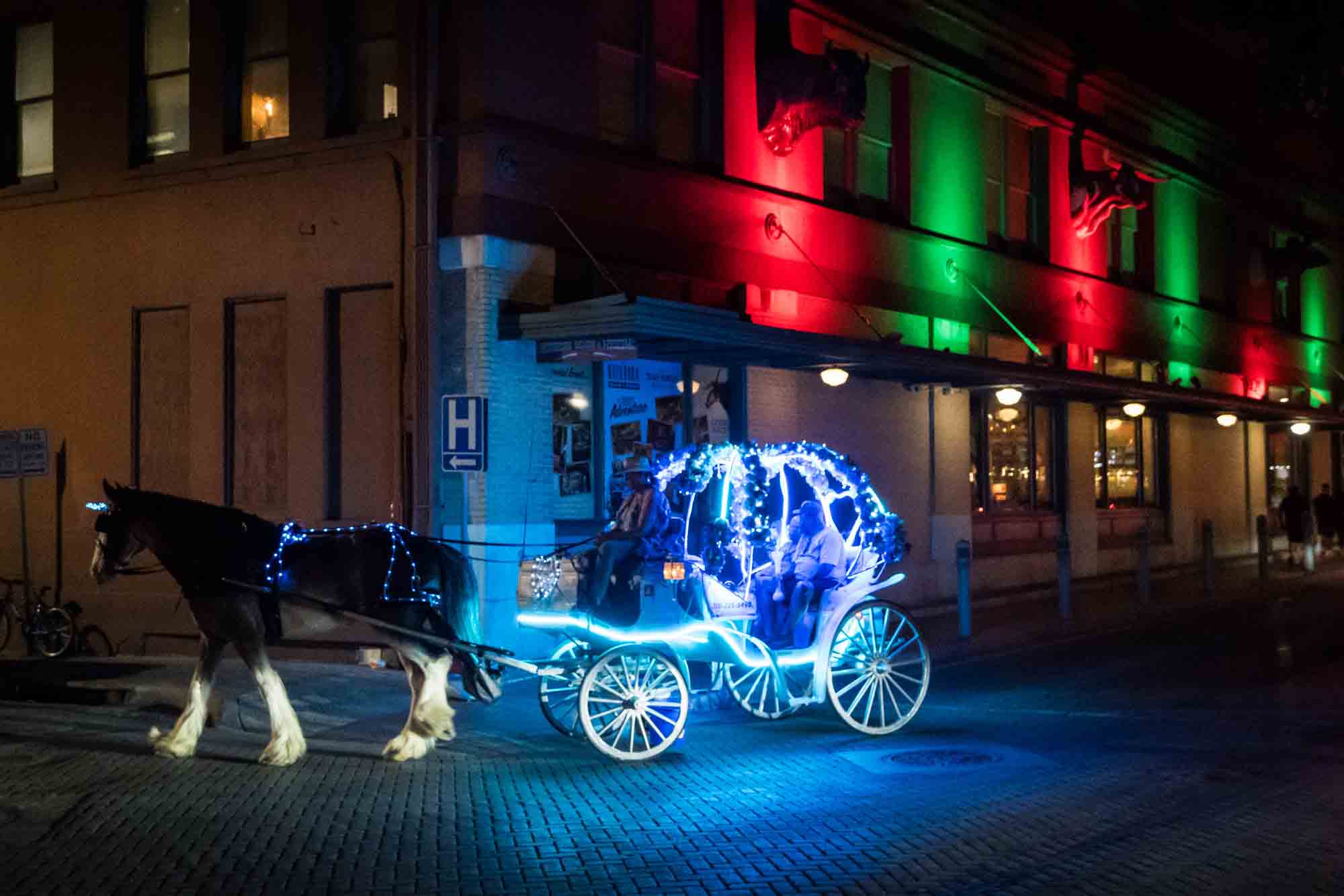 Horse carriage lit up in neon blue colors at night in San Antonio