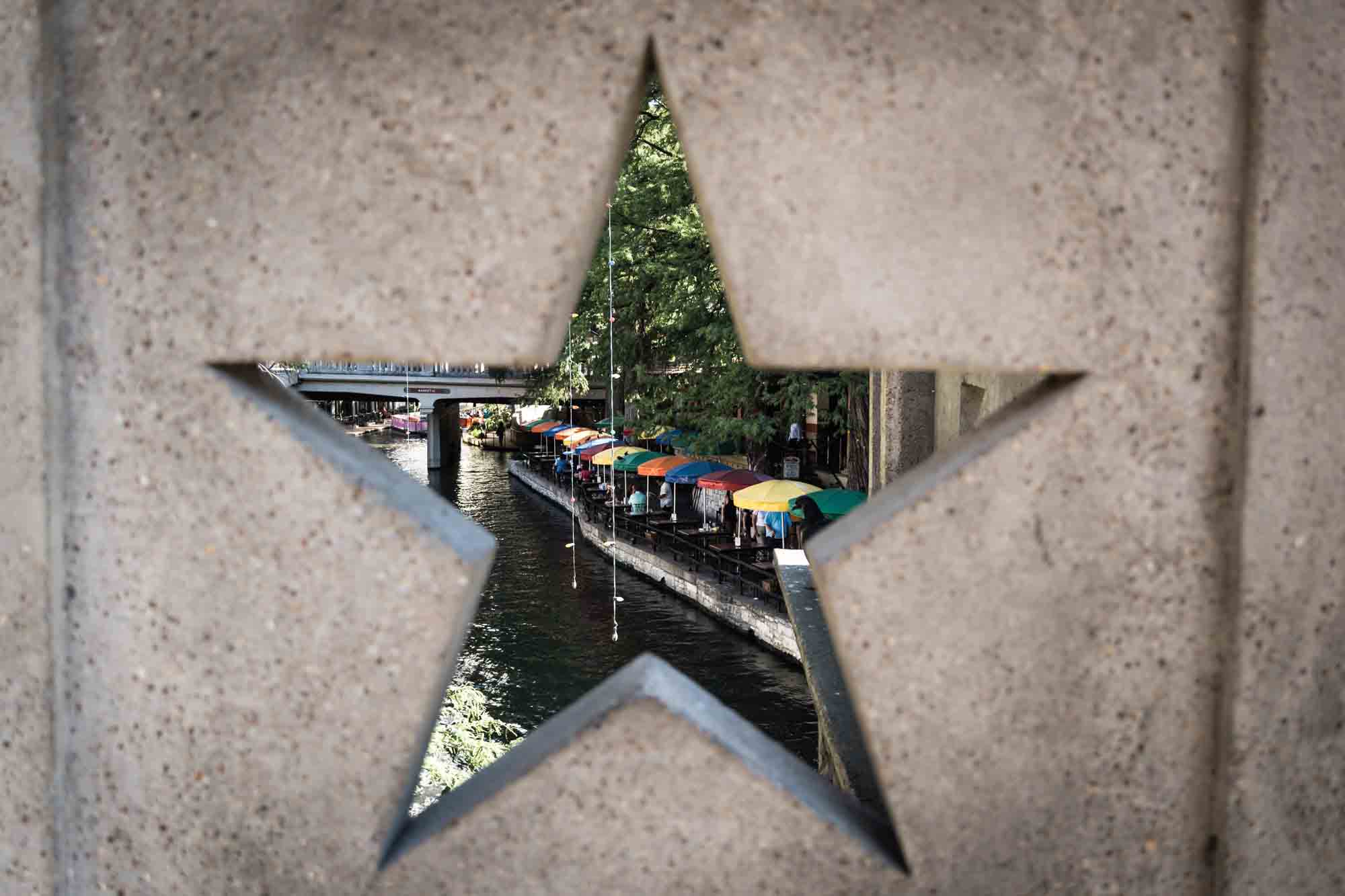 View of colorful umbrellas and Riverwalk through star window in bridge in San Antonio