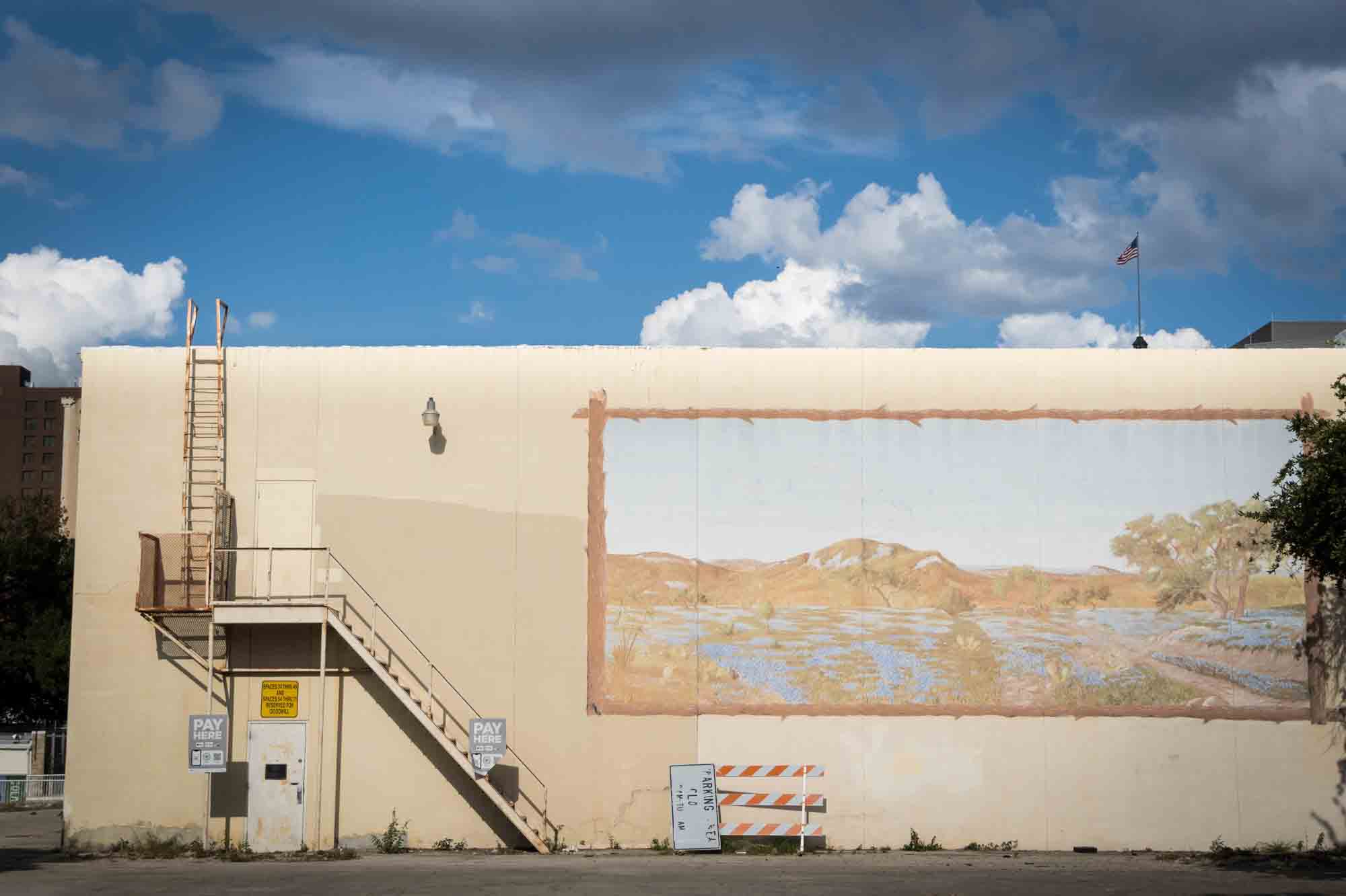 A faded mural of a landscape against a beige building in San Antonio