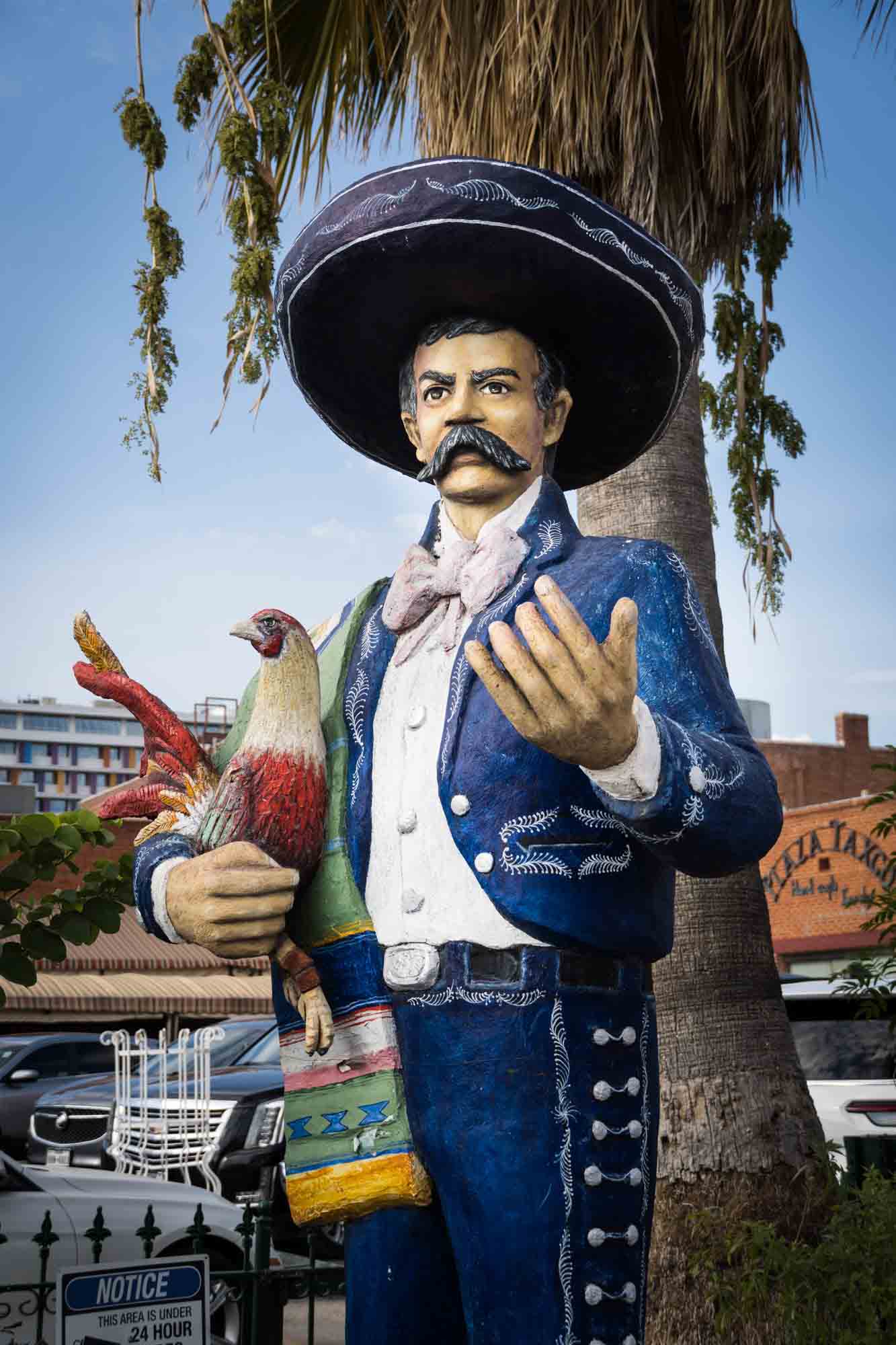 A statue of a mariachi holding a chicken in San Antonio