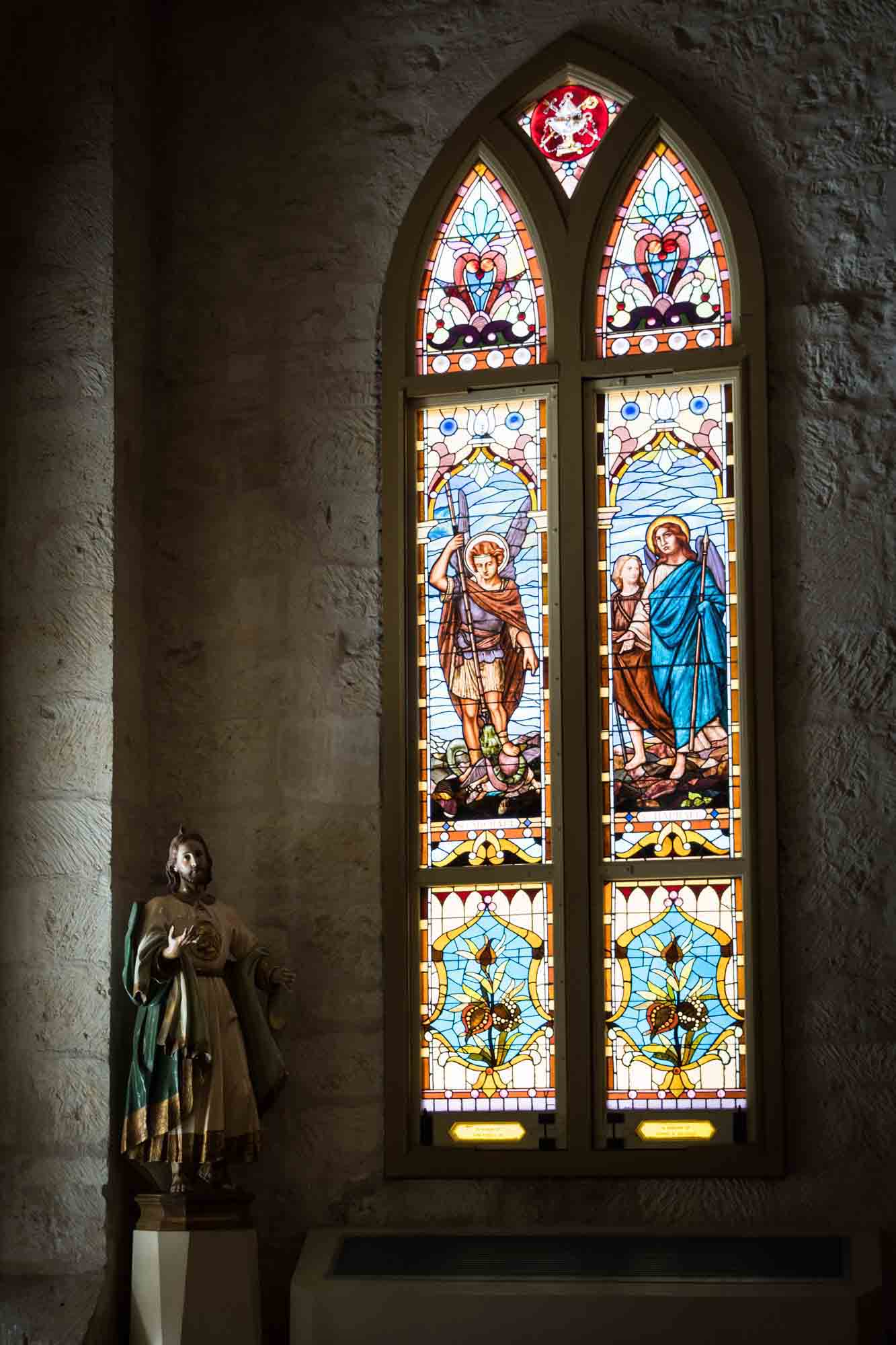 Colorful stained glass window and religious statue in the San Fernando Cathedral in San Antonio