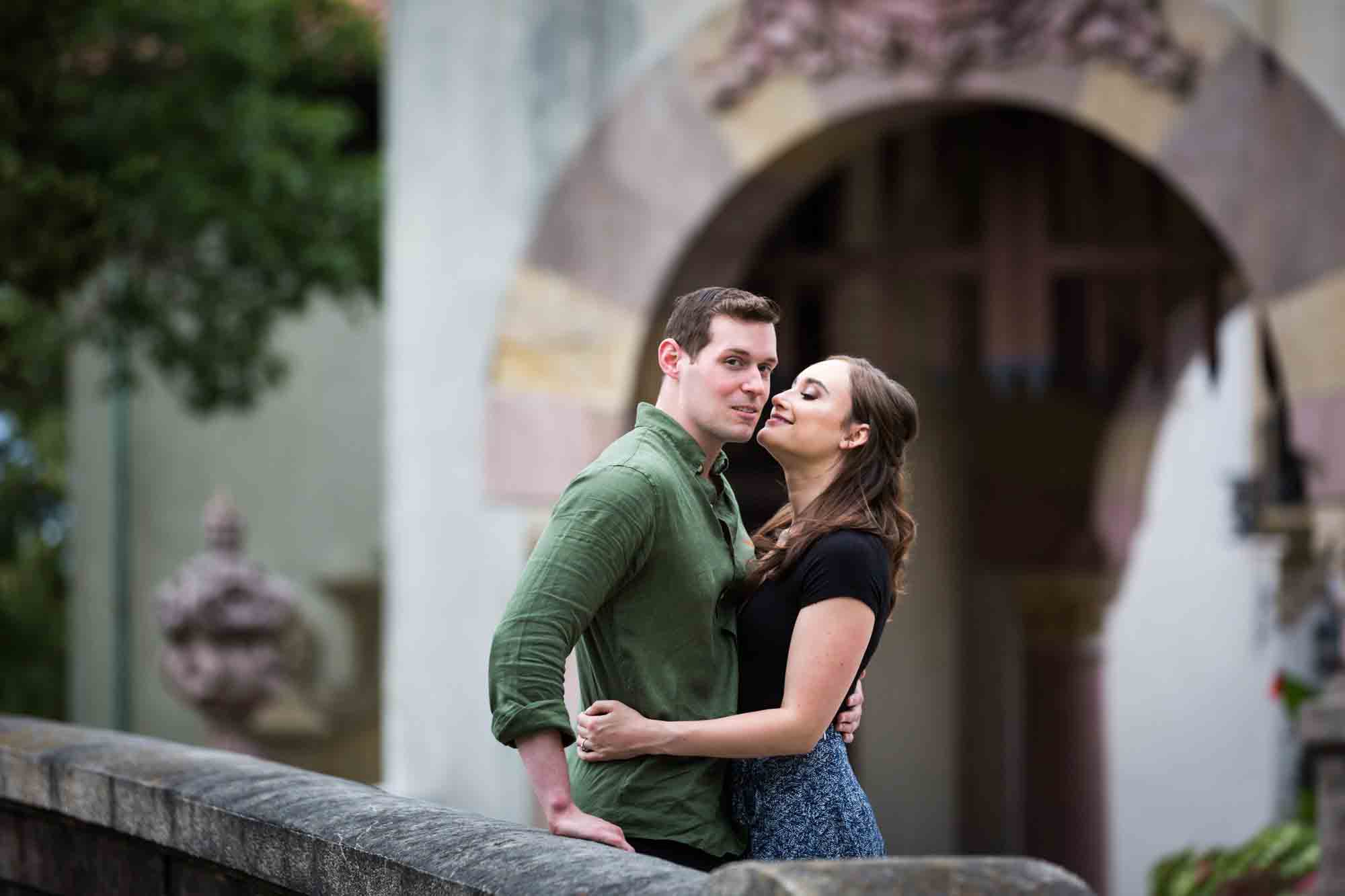 Vanderbilt Museum engagement photos of couple kissing on bridge in front of stone gate