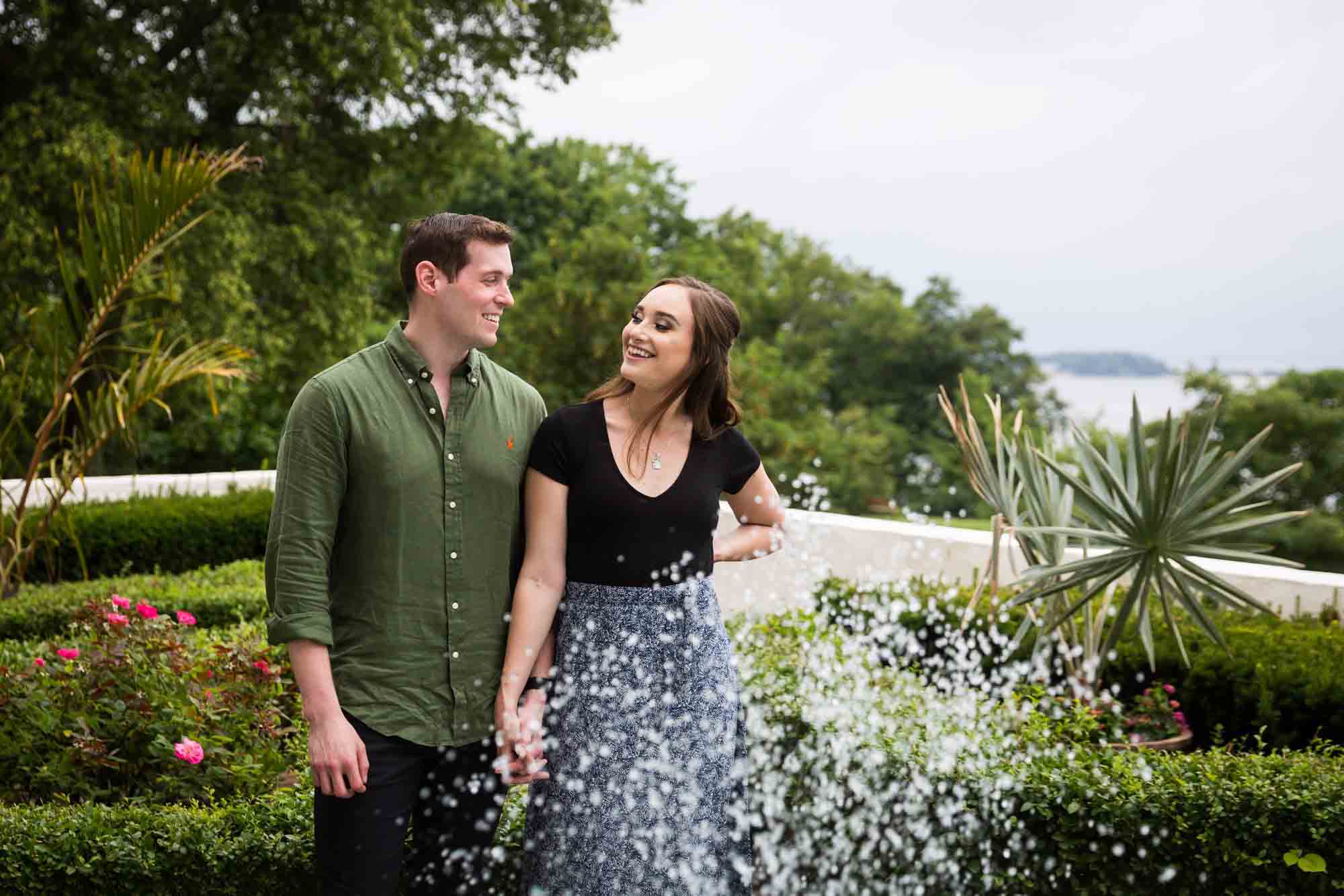 Couple looking at each other behind spraying water of fountain at Vanderbilt Museum