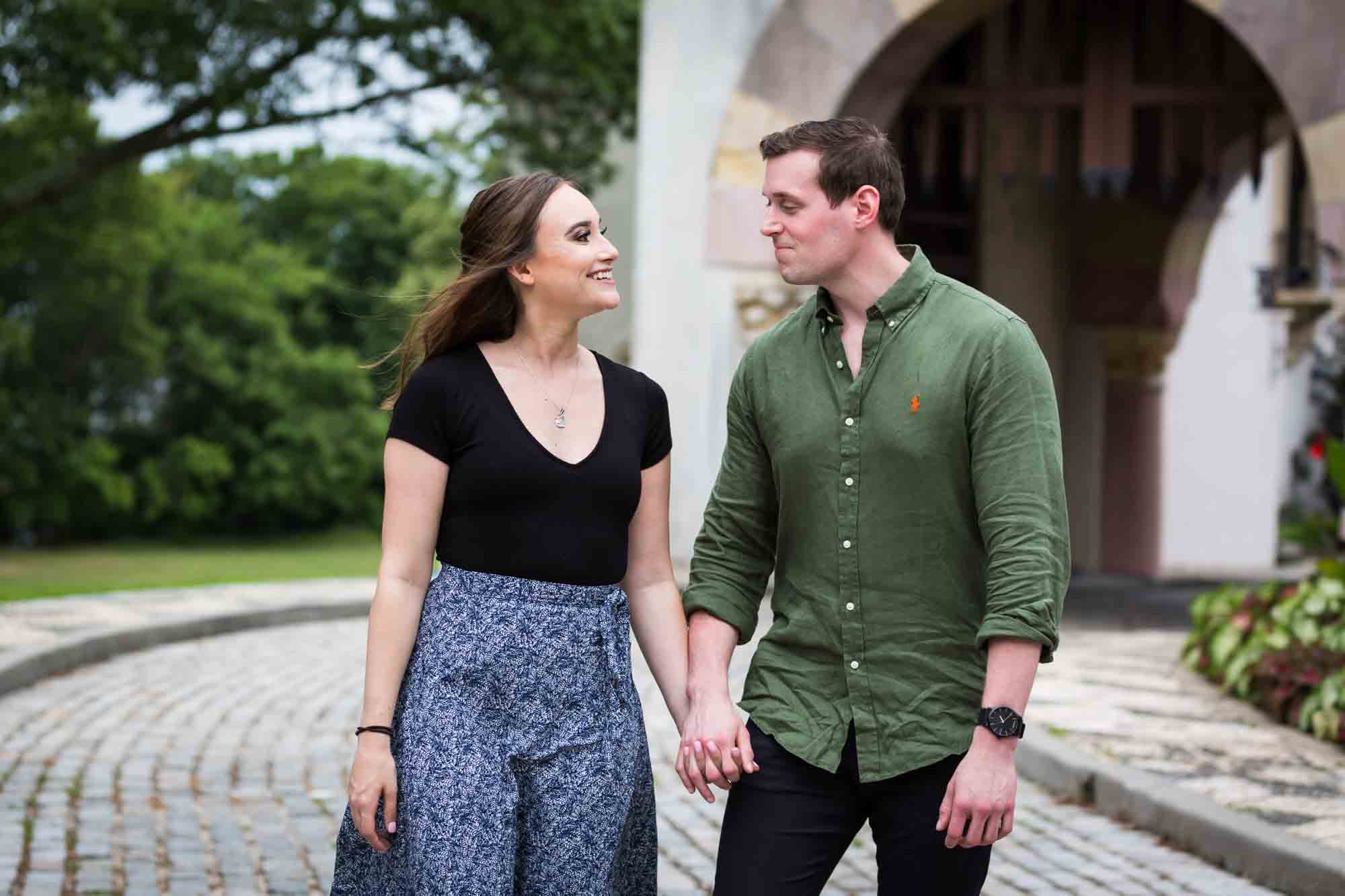 Couple holding hands and walking along cobblestone pathway