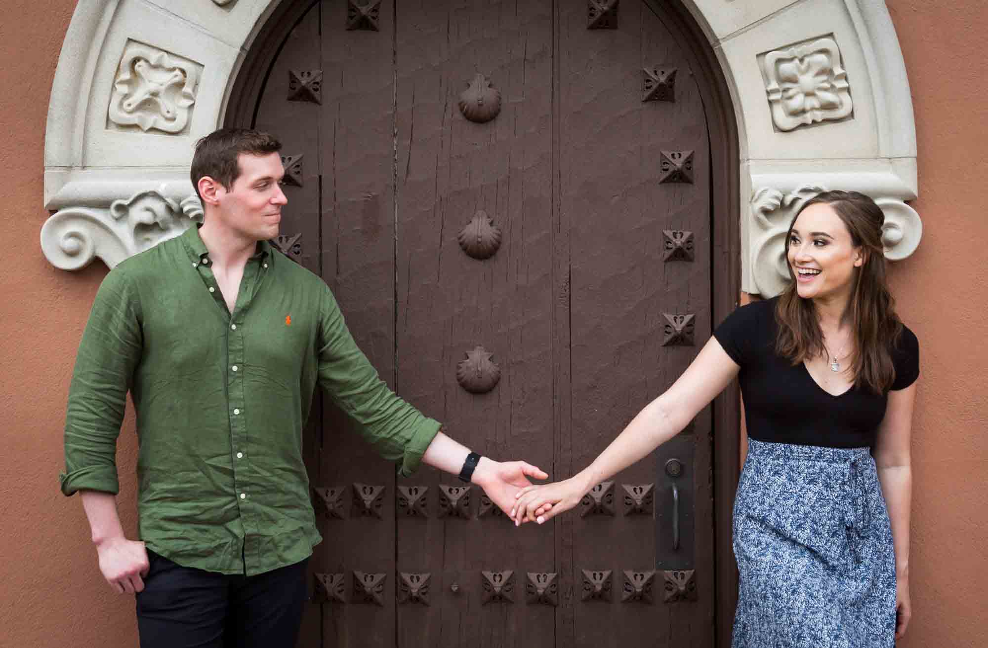 Couple holding hands in front of intricate wooden door at the Vanderbilt Museum