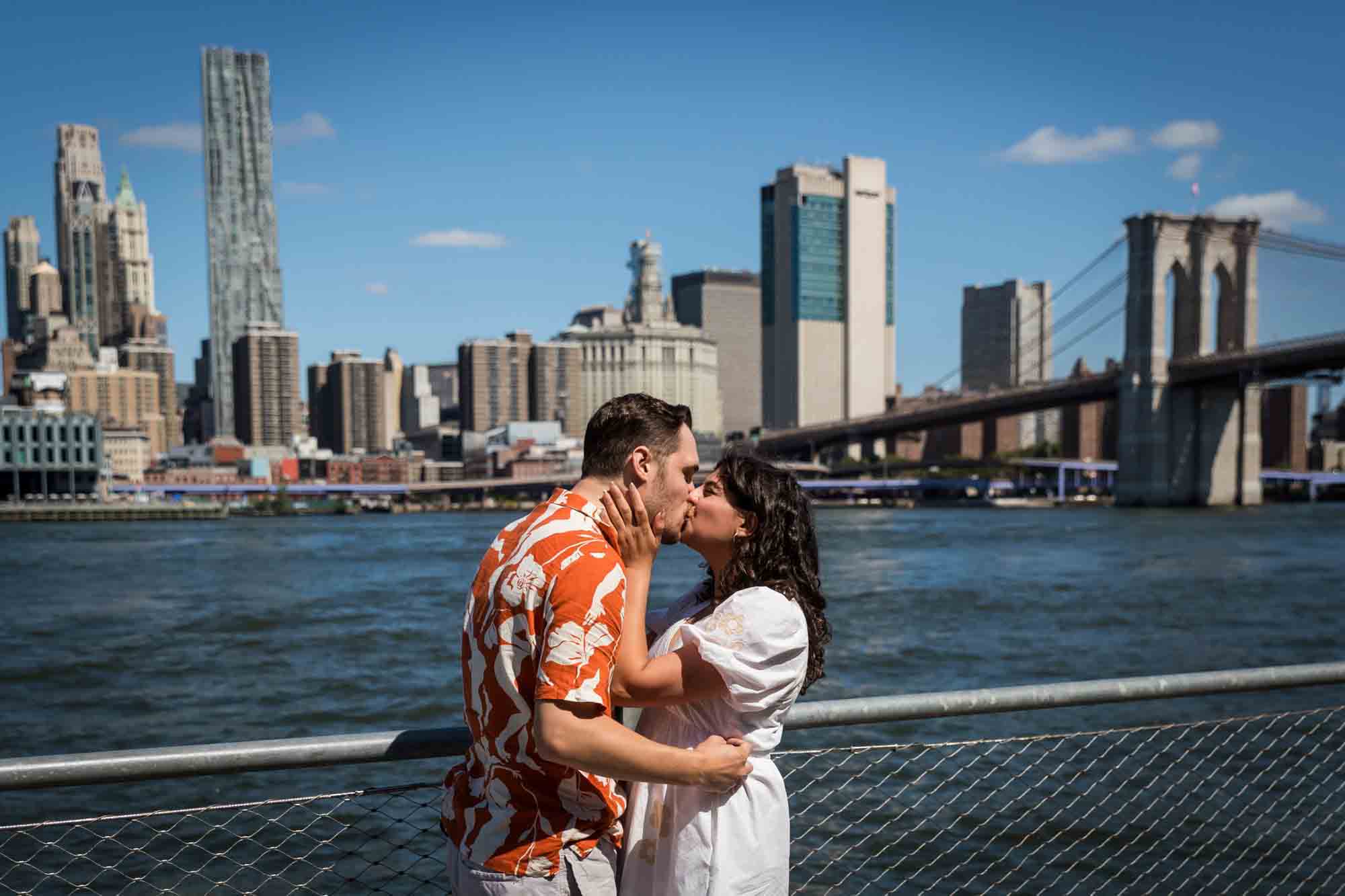 Couple kissing in front of waterfront in Brooklyn Bridge Park