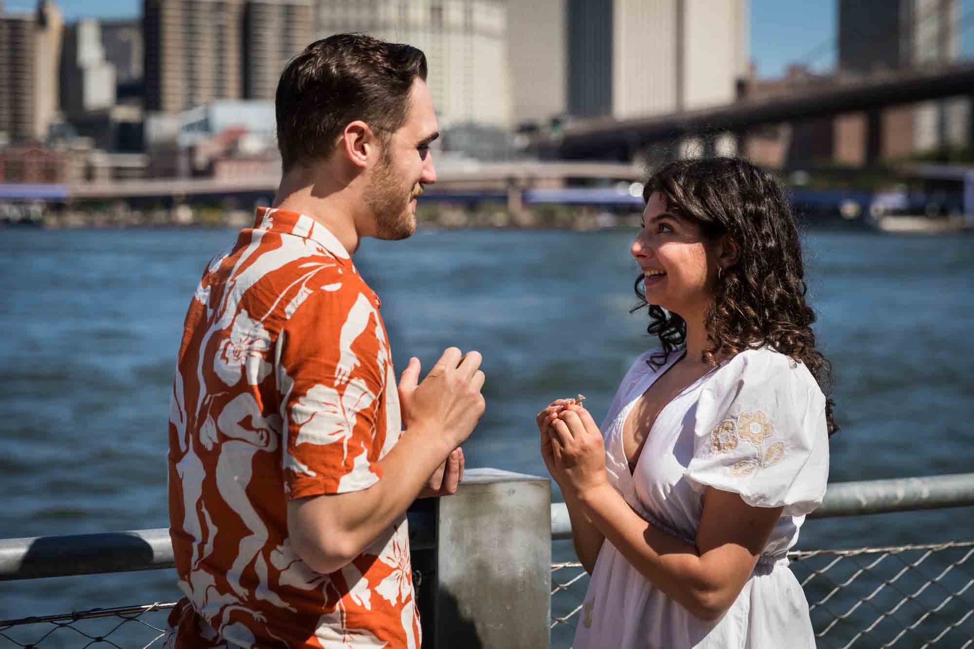 Couple looking at each other in front of waterfront in Brooklyn Bridge Park