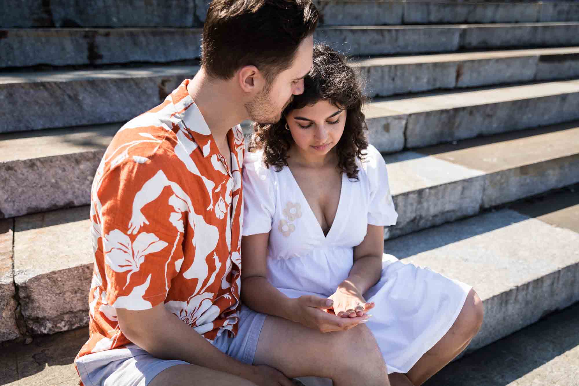 Couple looking at engagement ring on woman's finger on Granite Steps in Brooklyn Bridge Park