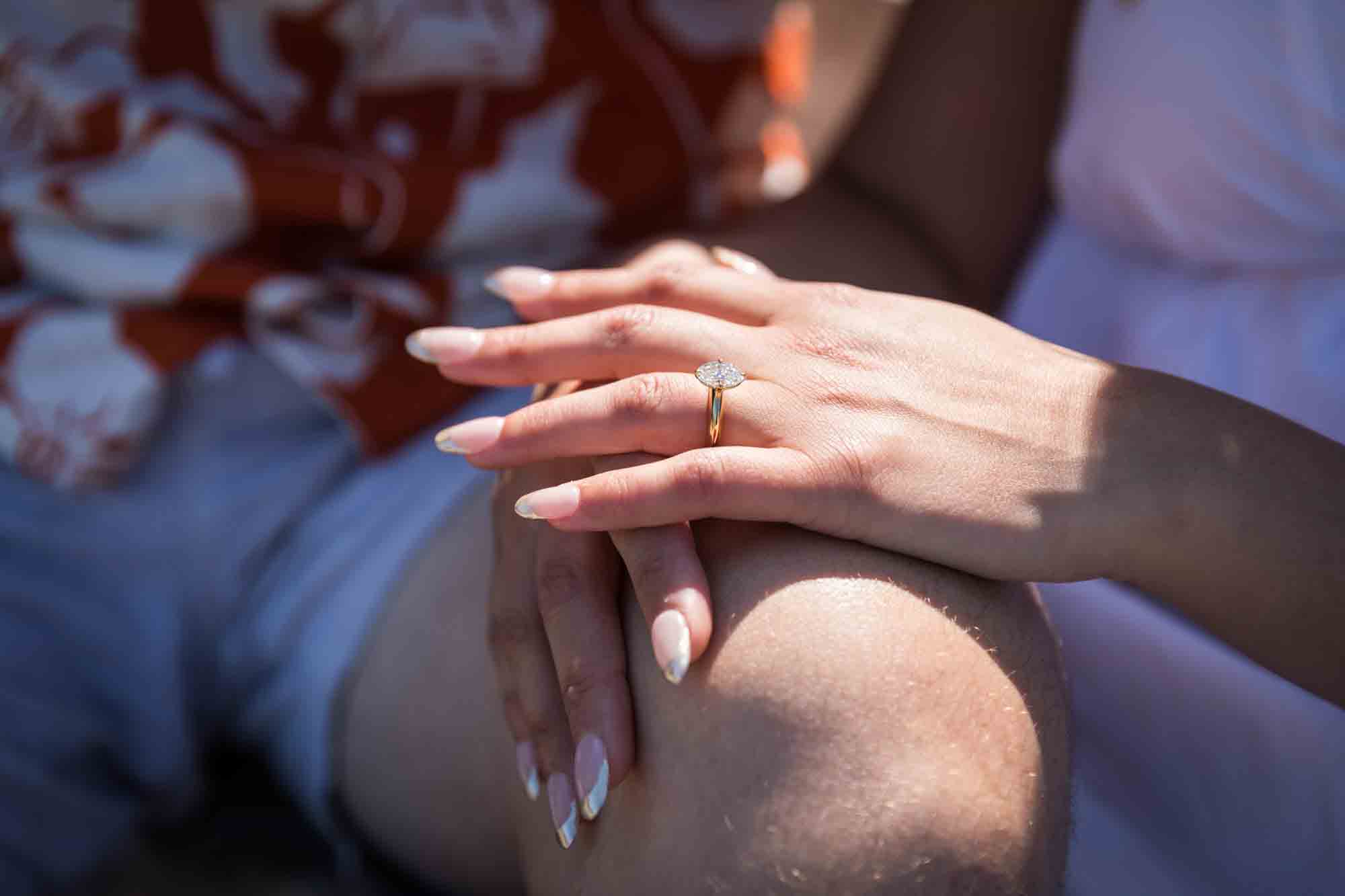 Close up of woman's hand showing oval engagement ring