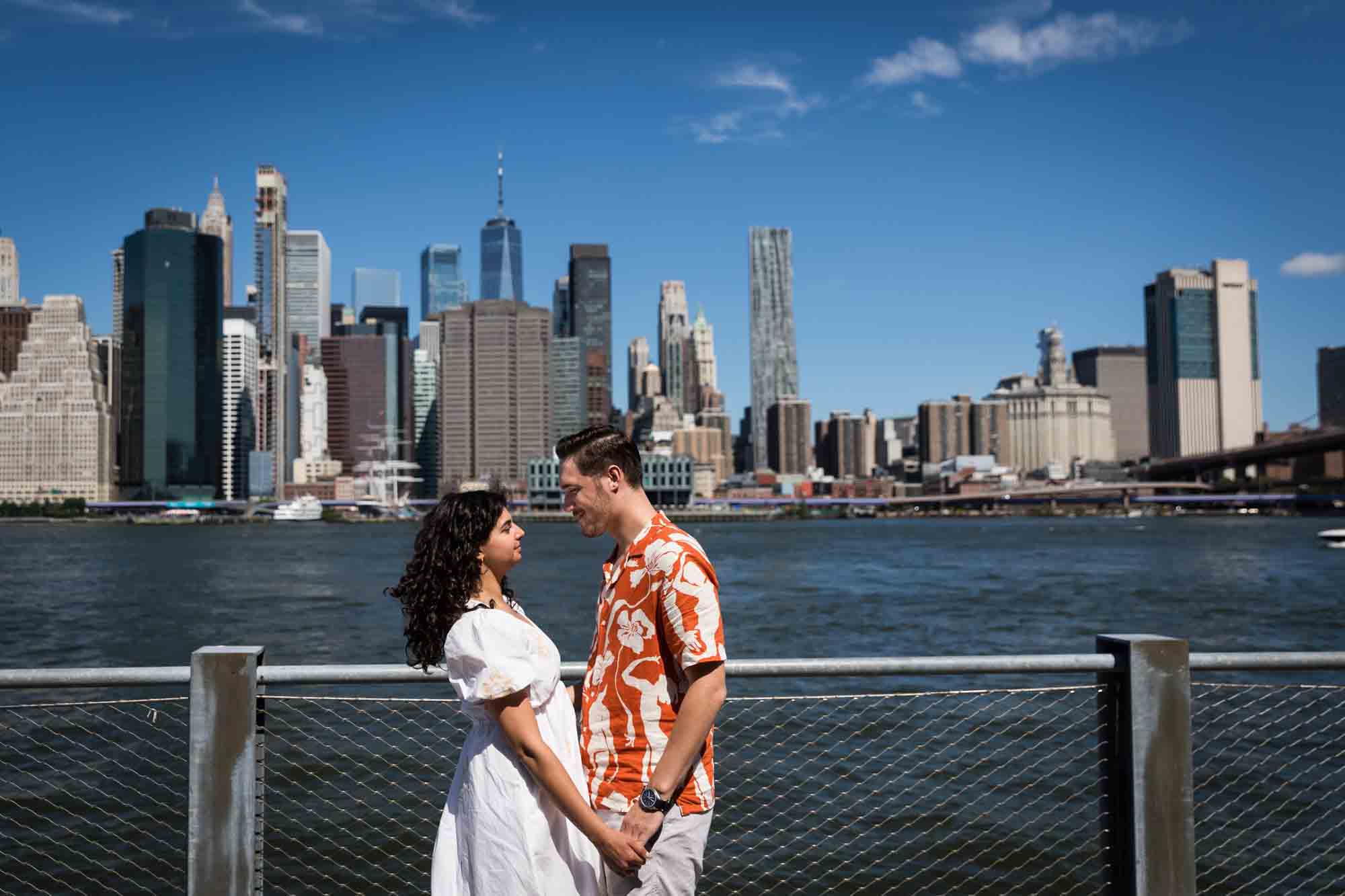 Couple holding hands by waterfront in Brooklyn Bridge Park