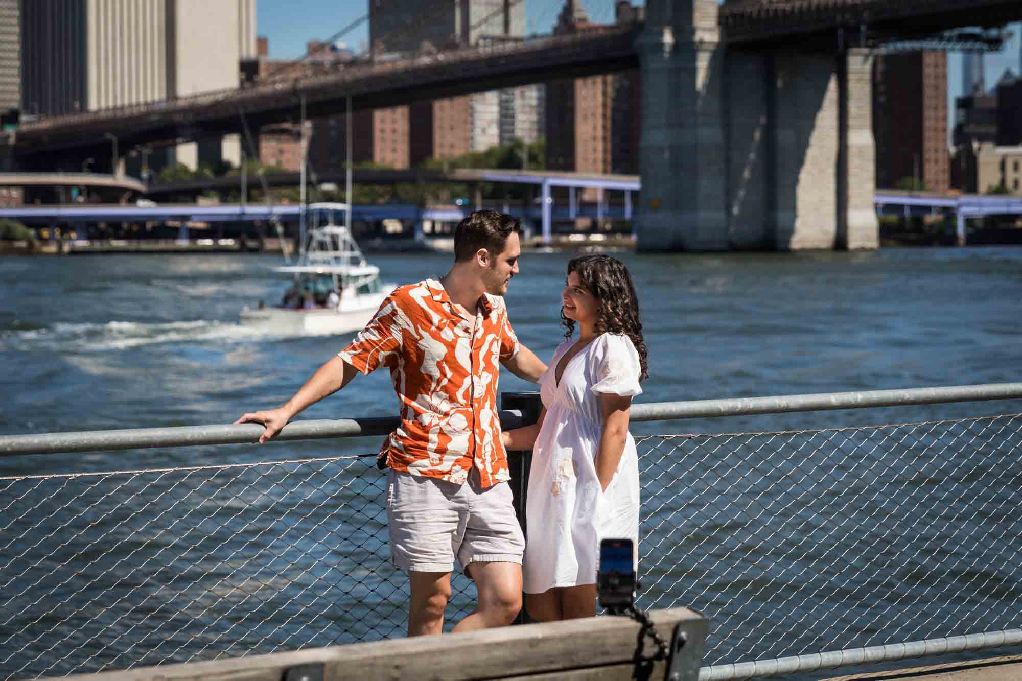 Couple standing together in front of waterfront in Brooklyn Bridge Park