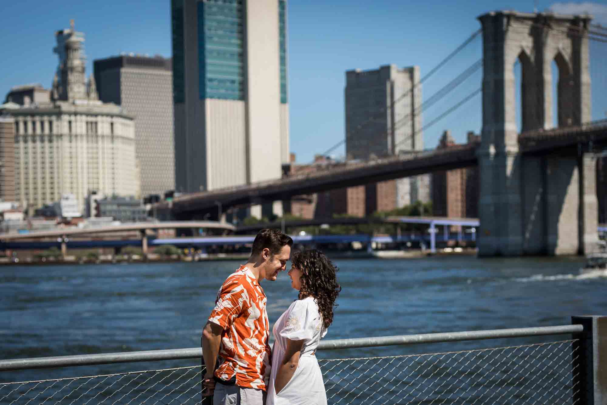 Couple standing together in front of waterfront in Brooklyn Bridge Park