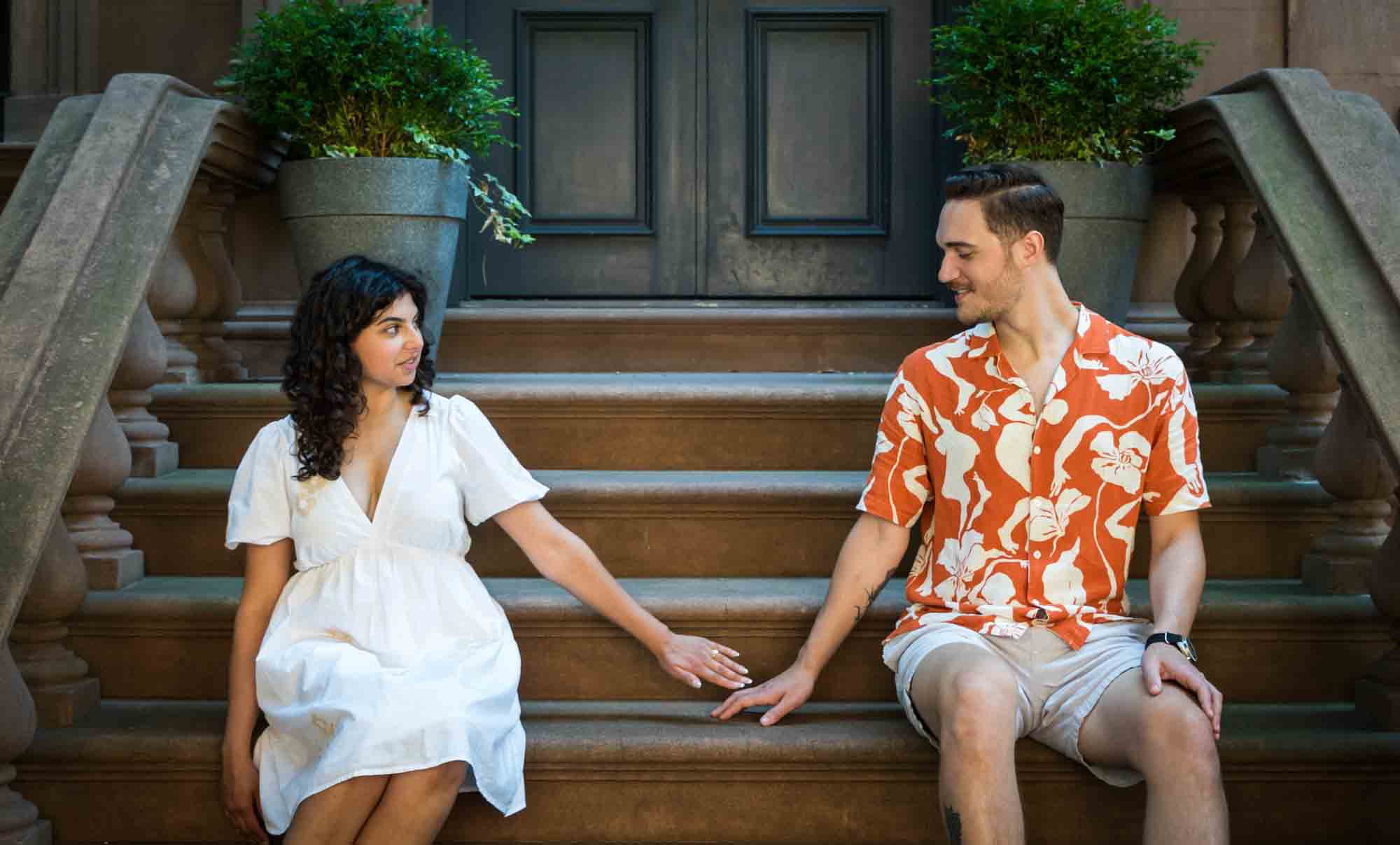 Couple sitting on brownstone staircase during a Brooklyn Heights surprise proposal