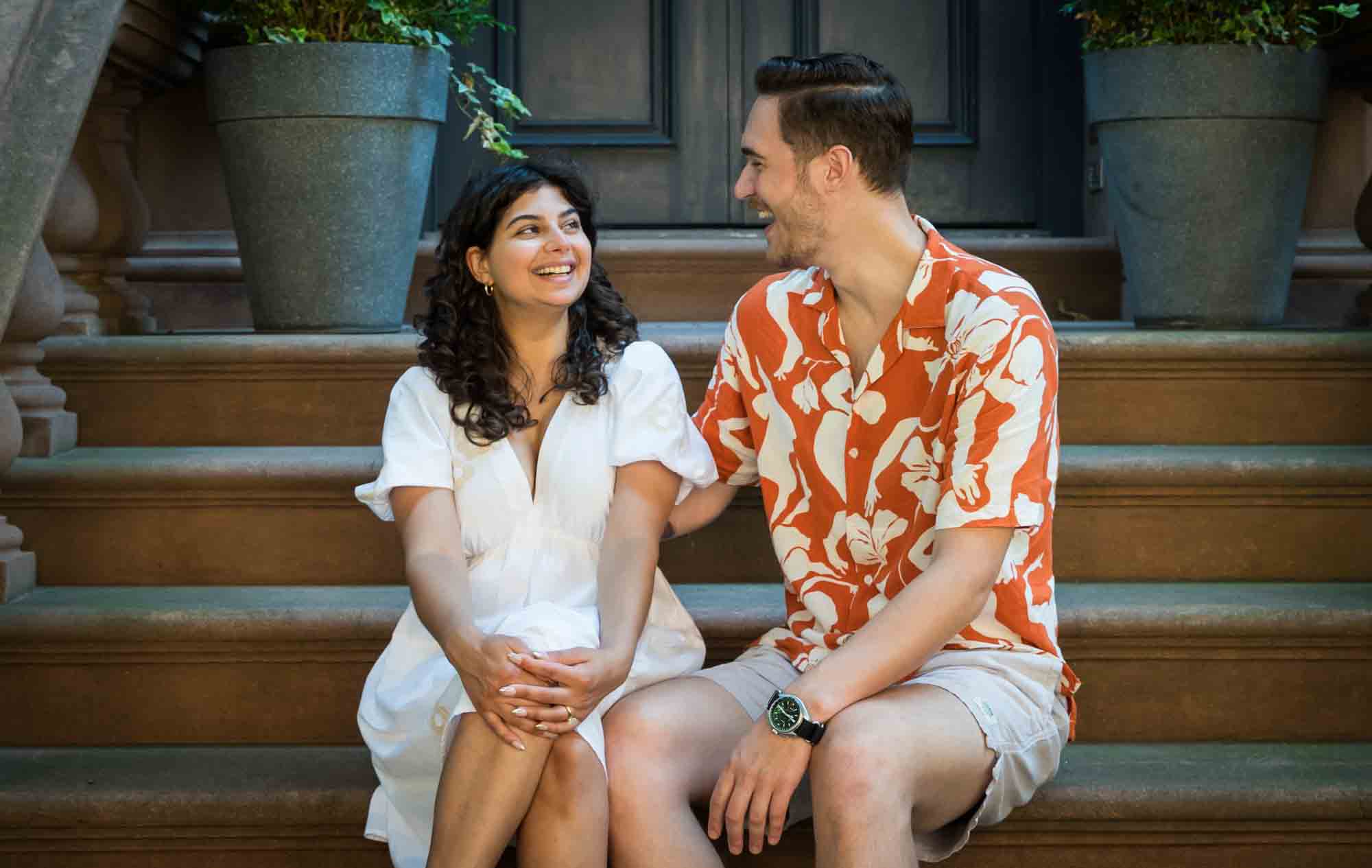 Couple laughing on brownstone staircase during a Brooklyn Heights surprise proposal