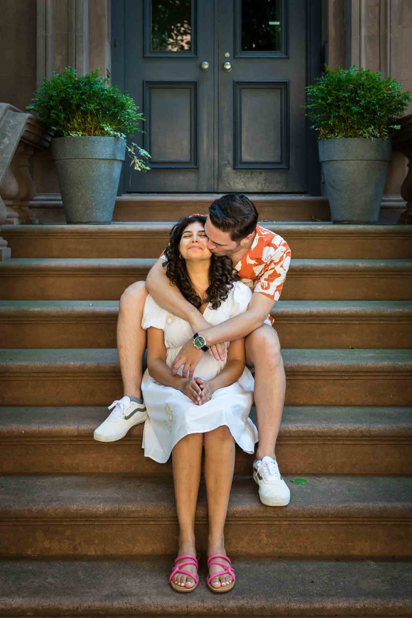 Couple hugging on brownstone staircase during a Brooklyn Heights surprise proposal