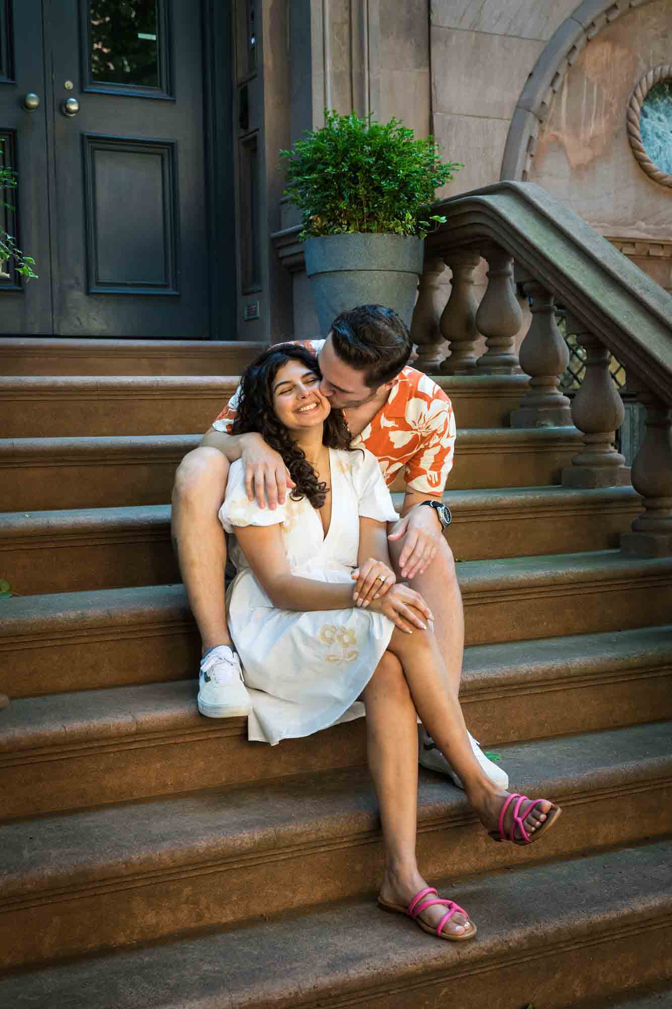 Couple hugging on brownstone staircase during a Brooklyn Heights surprise proposal